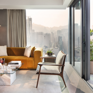 Luxurious living room at The Hari Hong Kong, featuring modern decor and stunning city views through large windows.
