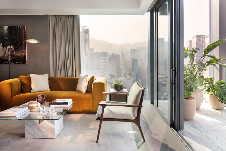 Luxurious living room at The Hari Hong Kong, featuring modern decor and stunning city views through large windows.