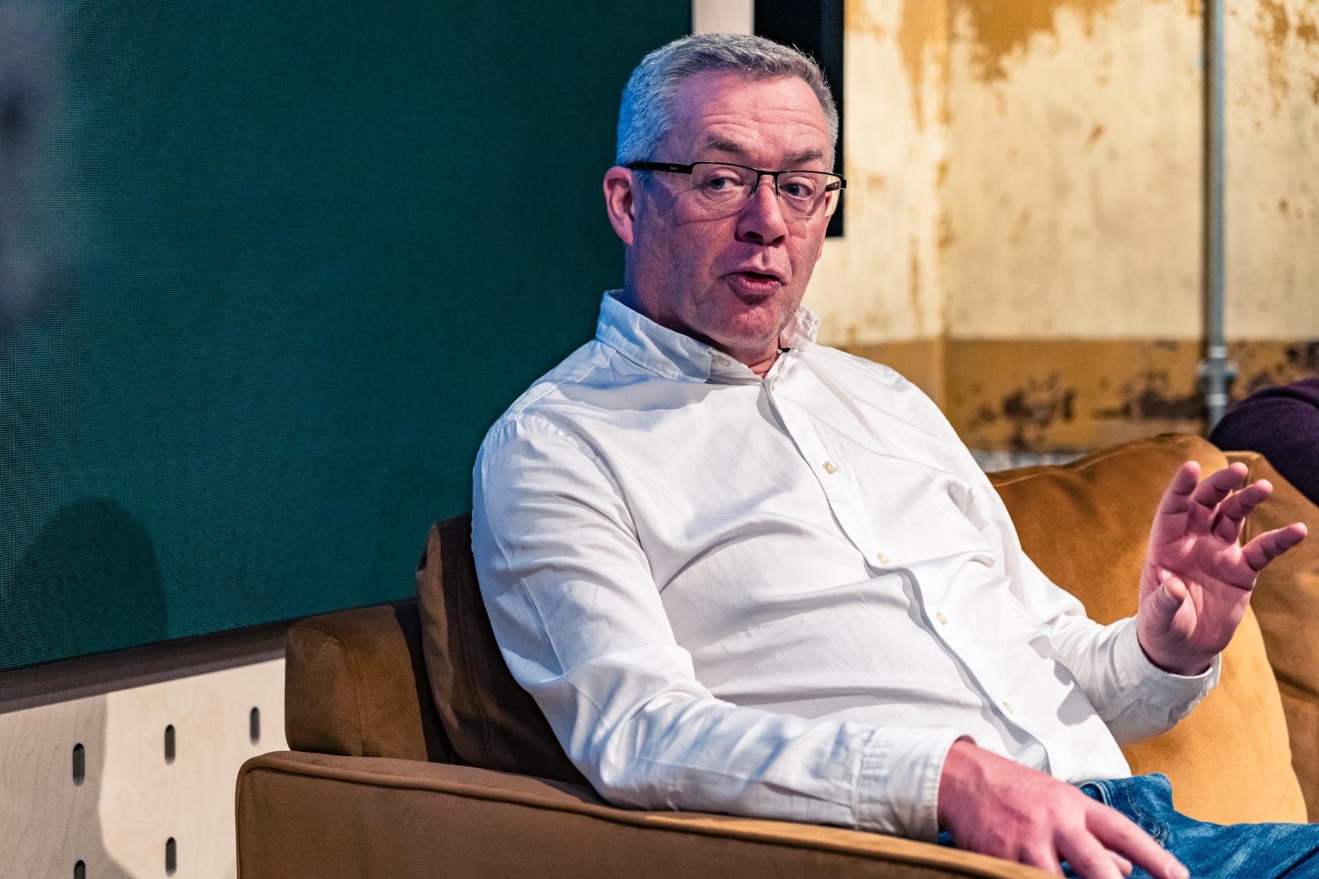 Discussion on materiality's role in reaching Net Zero, featuring a speaker in a casual setting.