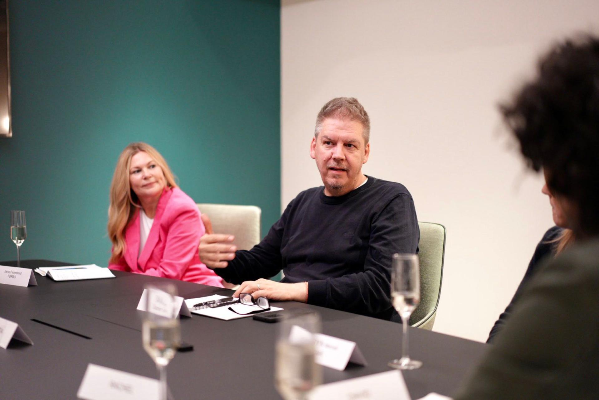 Participants engaged in a workplace discussion at a round table, highlighting modern work dynamics and collaboration.