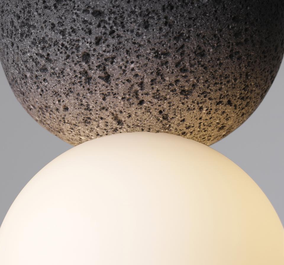 Origo lighting fixture featuring volcanic rock and glass, showcasing a fusion of organic and geometric design elements.