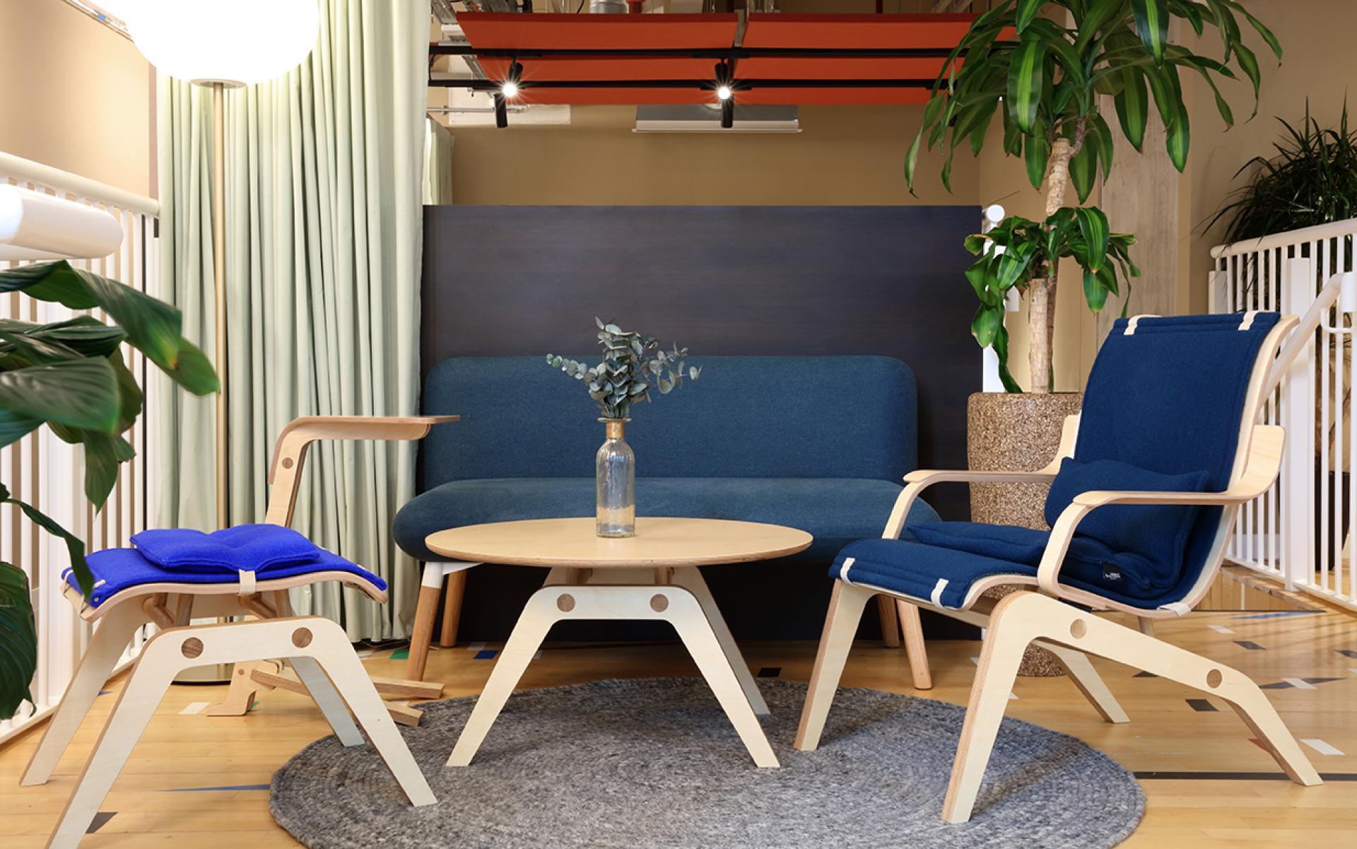 Modern social hub featuring sustainable furniture, including a blue couch, wooden chairs, and a round table at Eden, New Bailey.