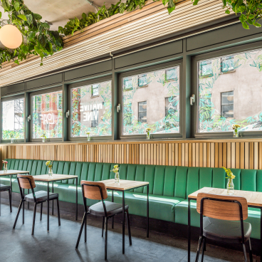 Bright and inviting café space at Bristol Loaf, featuring green seating, natural light, and decorative plants.