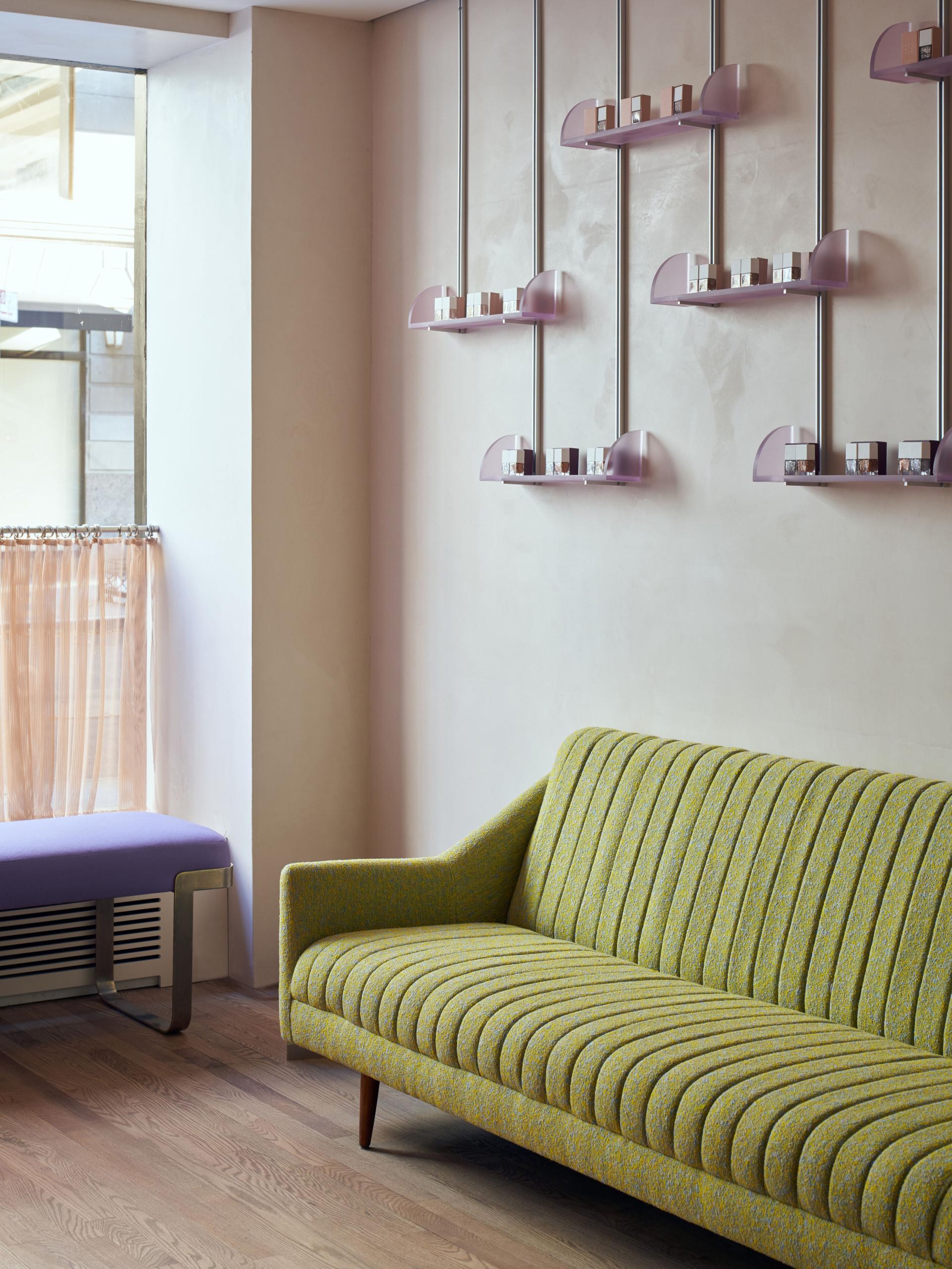 Stylish green striped sofa and modern display shelves featuring nail products in a chic New York nail studio.