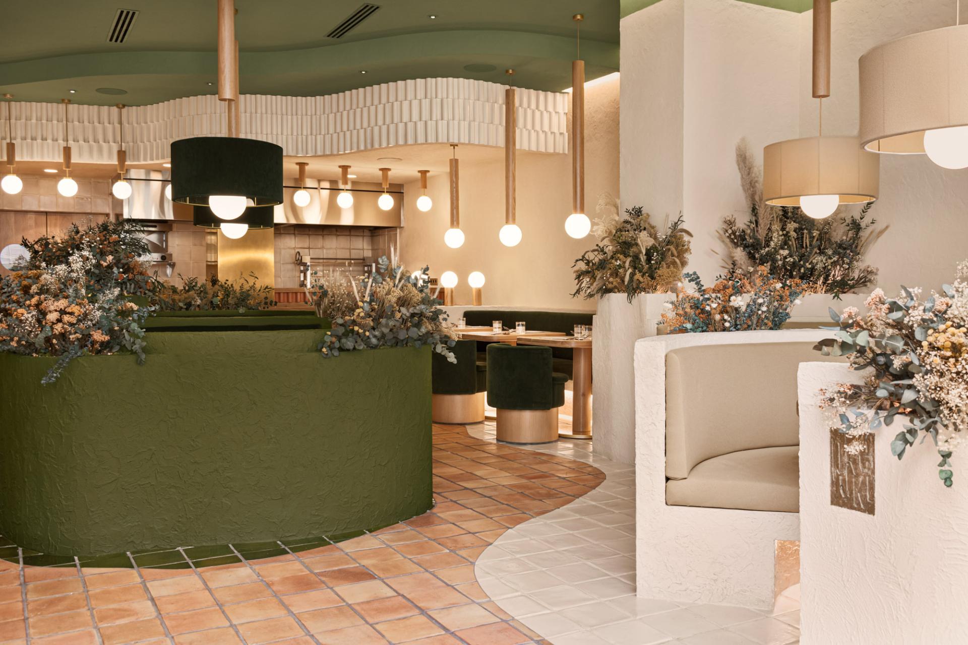 Modern restaurant interior featuring green accents, floral decor, and elegant seating, designed by Masquespacio for Pukkel in Huesca.