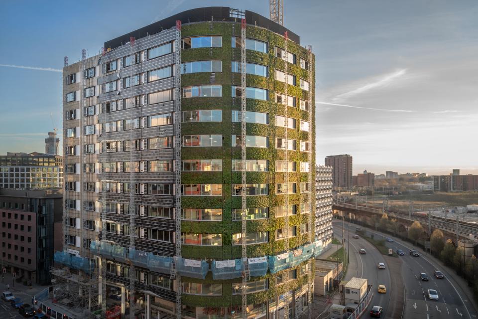 Sustainable architecture featuring a green façade on a modern building in Manchester's urban landscape, enhancing biodiversity.