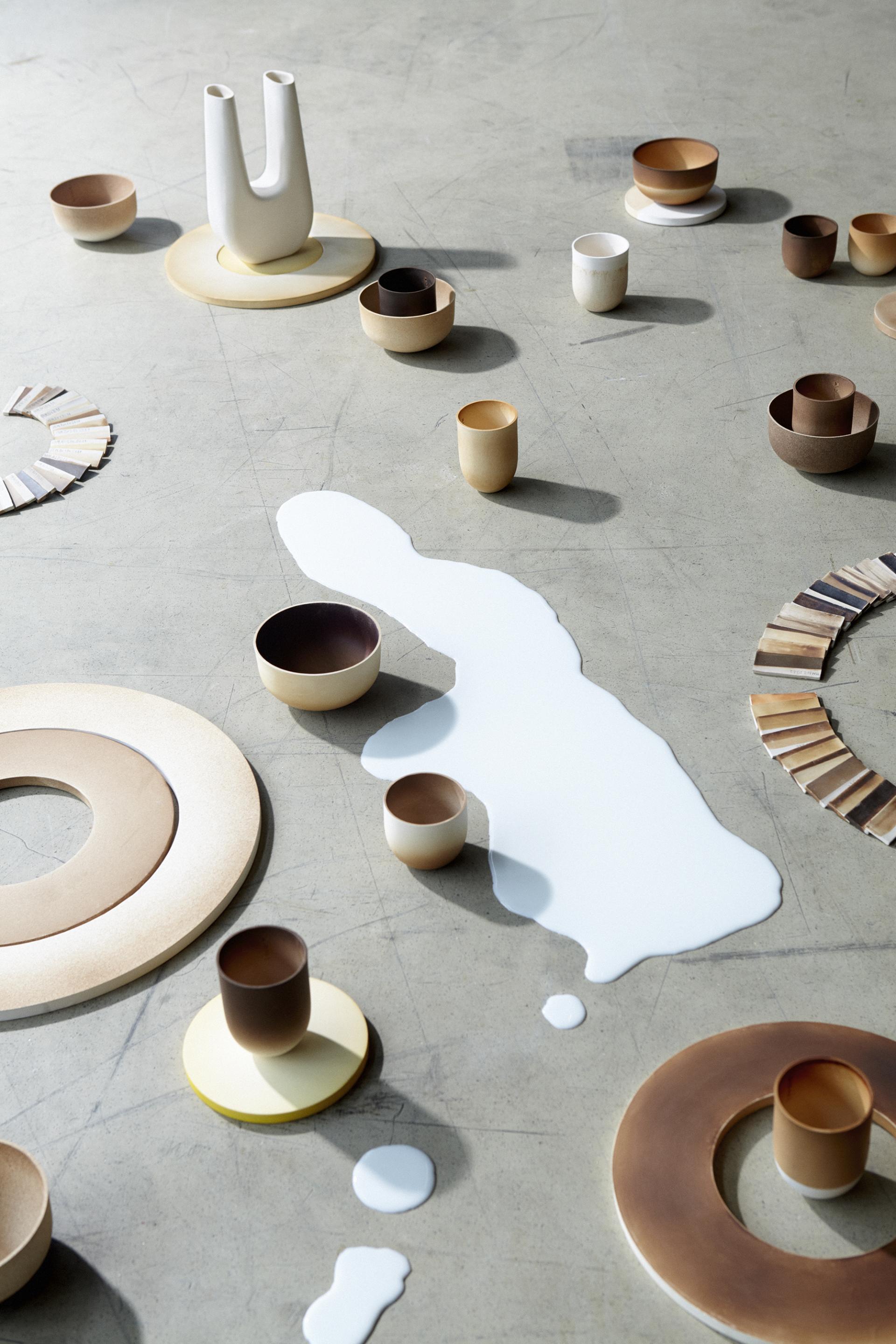 Innovative biomaterials displayed as modern ceramic vessels and components arranged artistically on a textured surface.