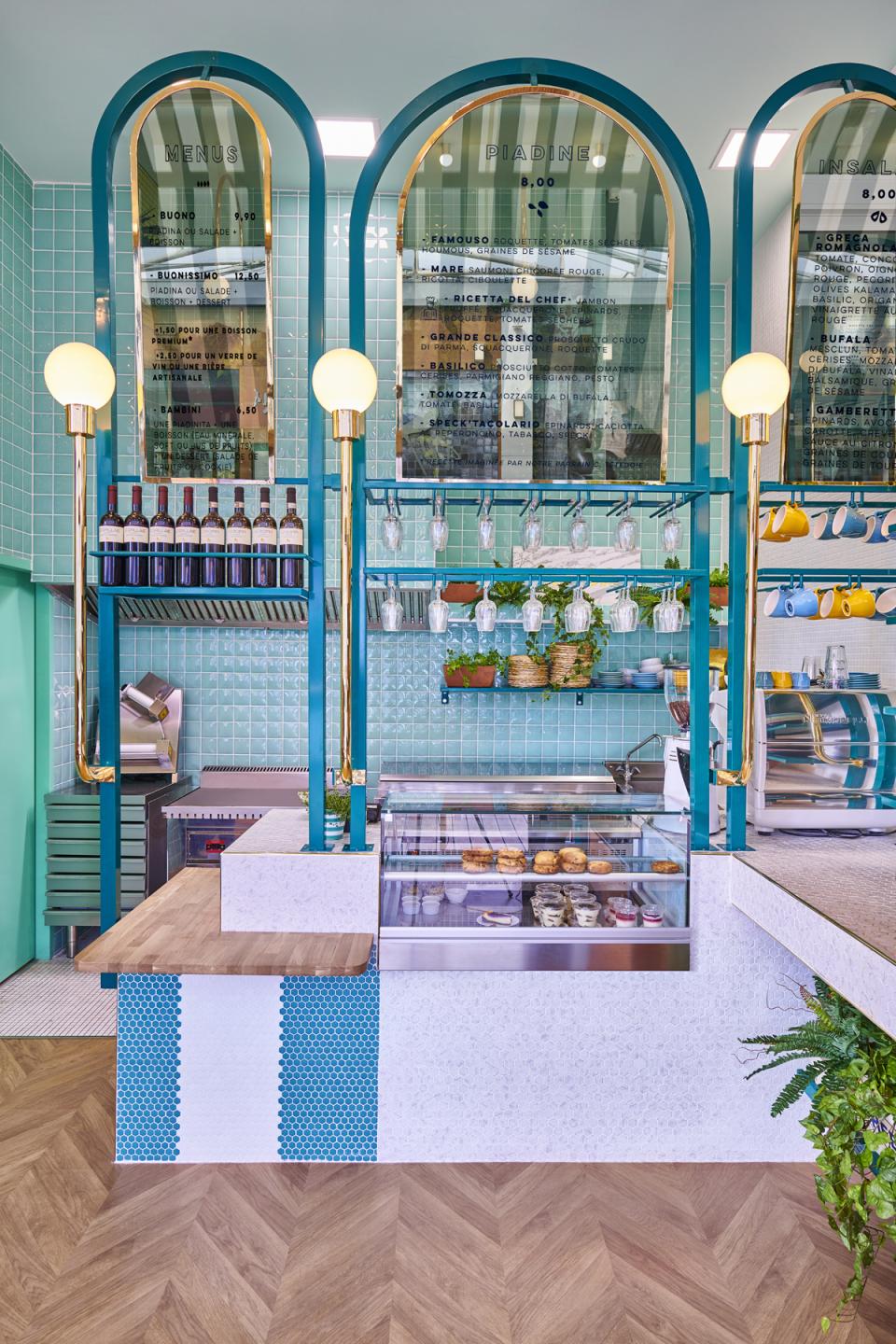 Colorful Italian restaurant interior featuring a menu display, wine bottles, and a dessert showcase, designed by Masquespacio in Lyon.