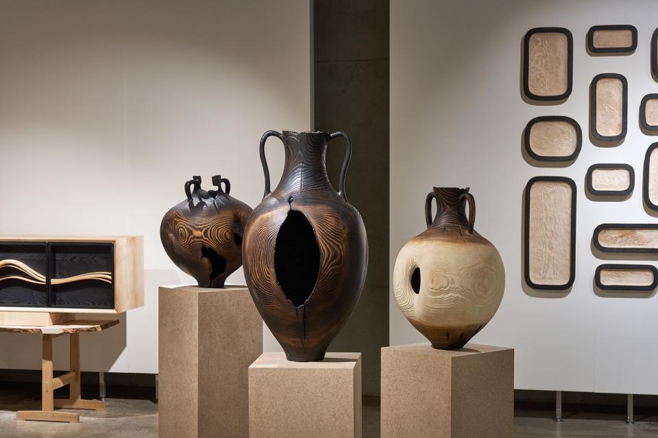 Artistic wooden vases crafted from Scottish ash, displayed prominently in a gallery setting, highlighting material intelligence.