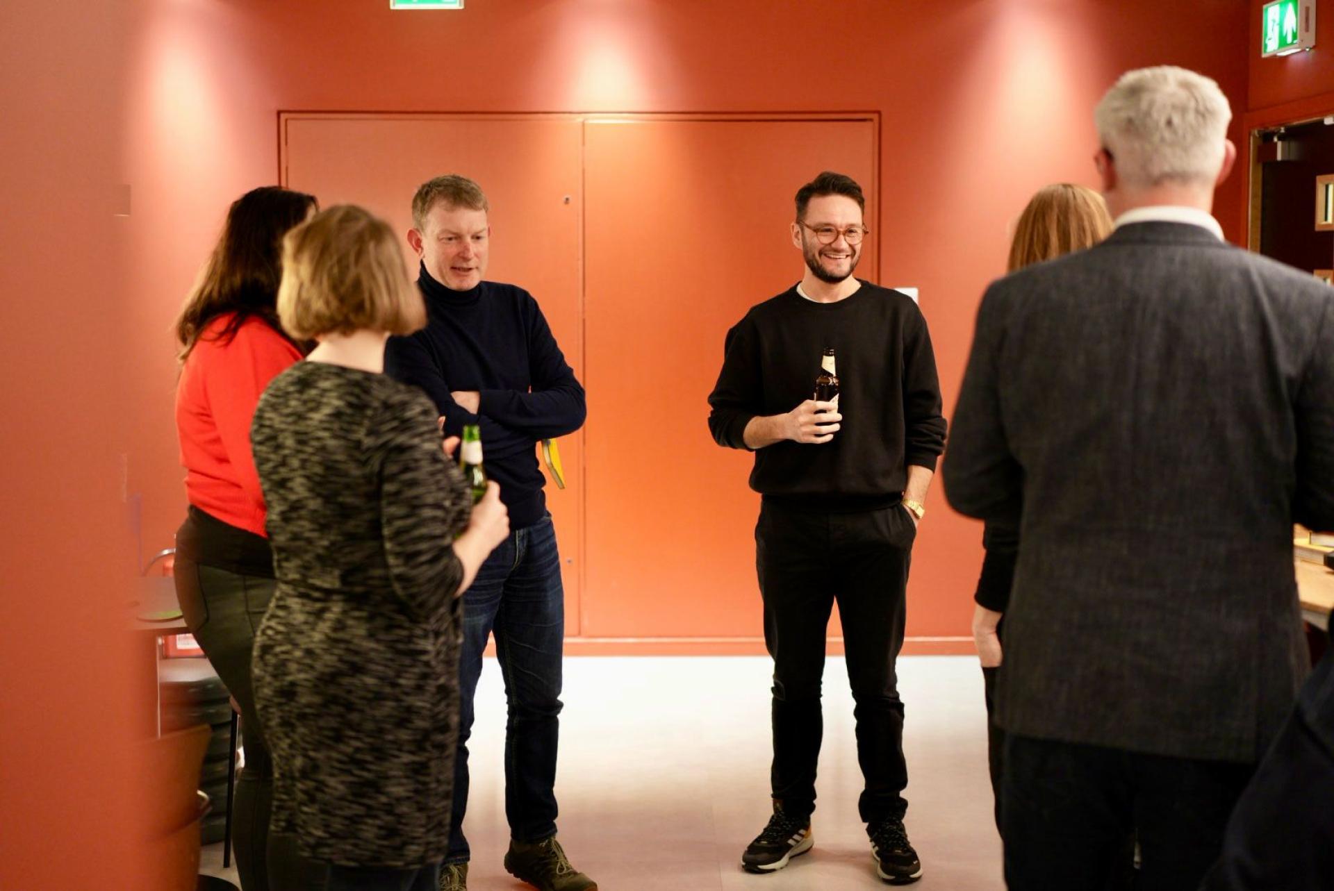 Group of professionals networking and enjoying drinks, discussing the future of workplace flexibility and culture.