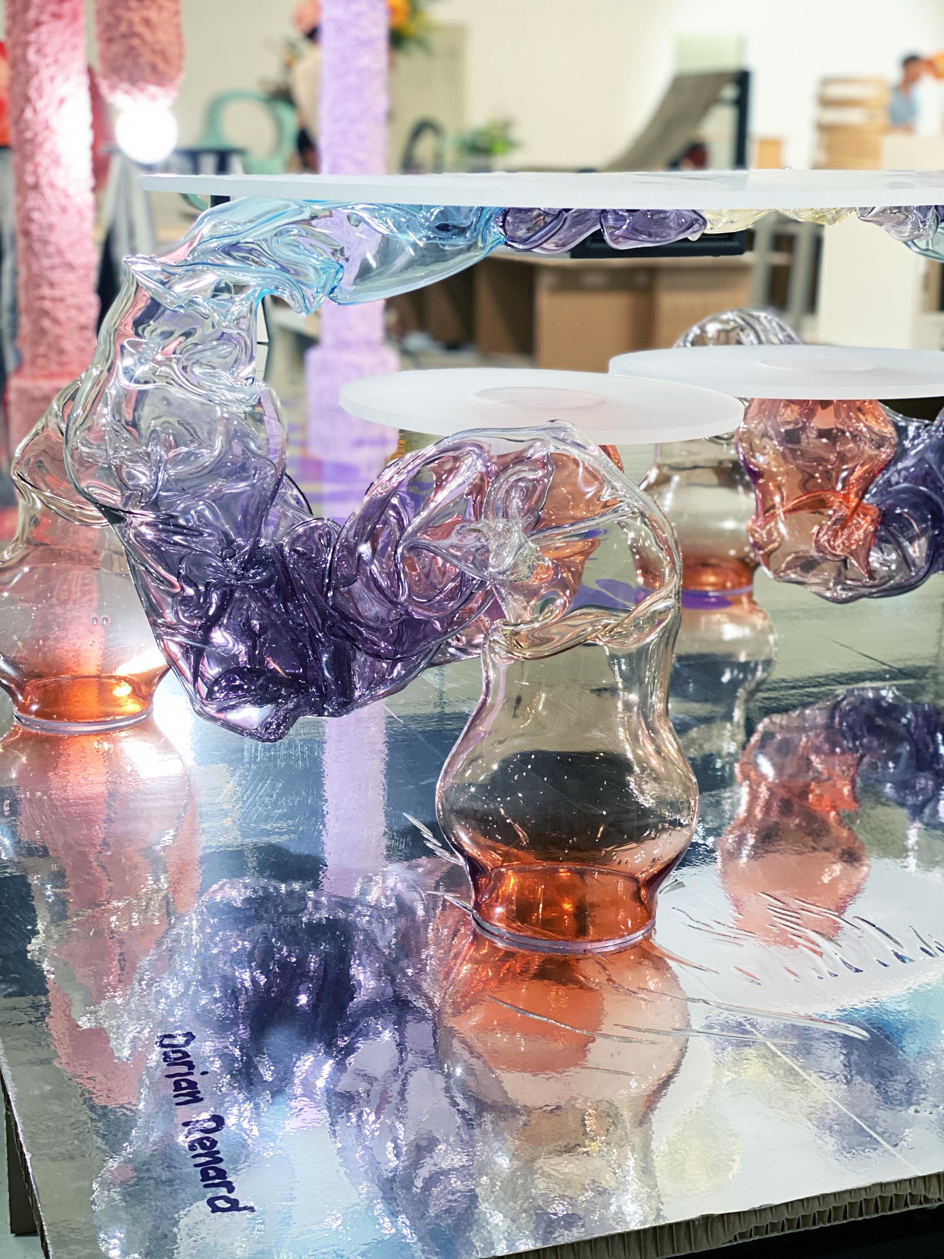 Colorful glass sculptures elegantly intertwined on a reflective surface, showcasing the creativity of the Matérialité collection at Paris Design Week.