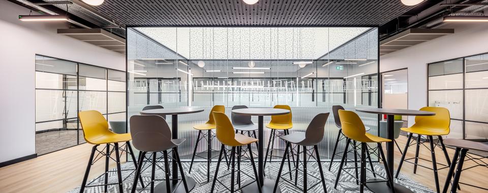 Stylish workspace featuring high tables and yellow bar stools in a modern office setting at The Bee House, Milton Park.