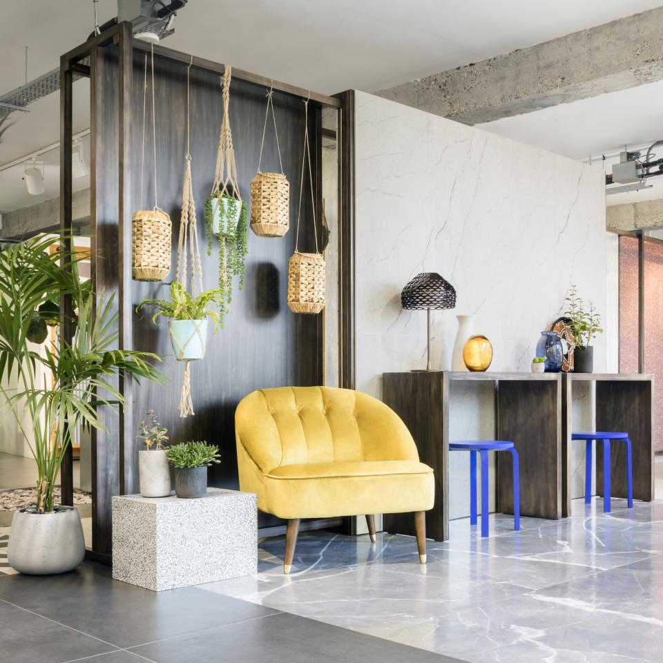 Stylish Clerkenwell showroom featuring a yellow armchair, hanging planters, and modern decor elements for architectural inspiration.