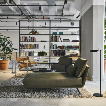 Stylish interior of a refurbished bread factory featuring modern furniture, bookshelves, and decorative plants by Studio Joanna Laajisto.