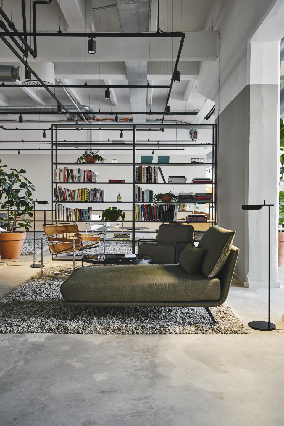 Stylish interior of a refurbished bread factory featuring modern furniture, bookshelves, and decorative plants by Studio Joanna Laajisto.