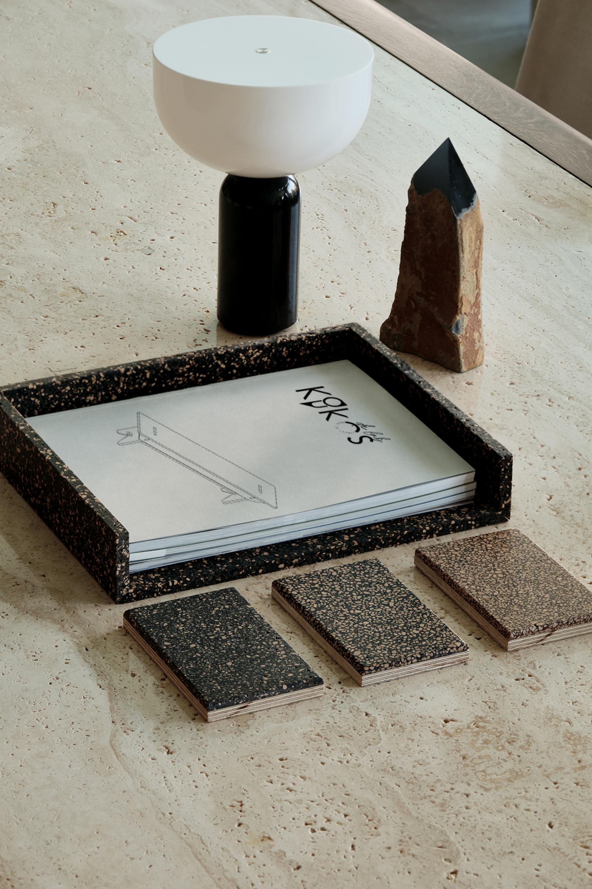 Stylish tabletop featuring biomaterials: a lamp, a stone, design sketches, and color samples showcasing sustainable products.