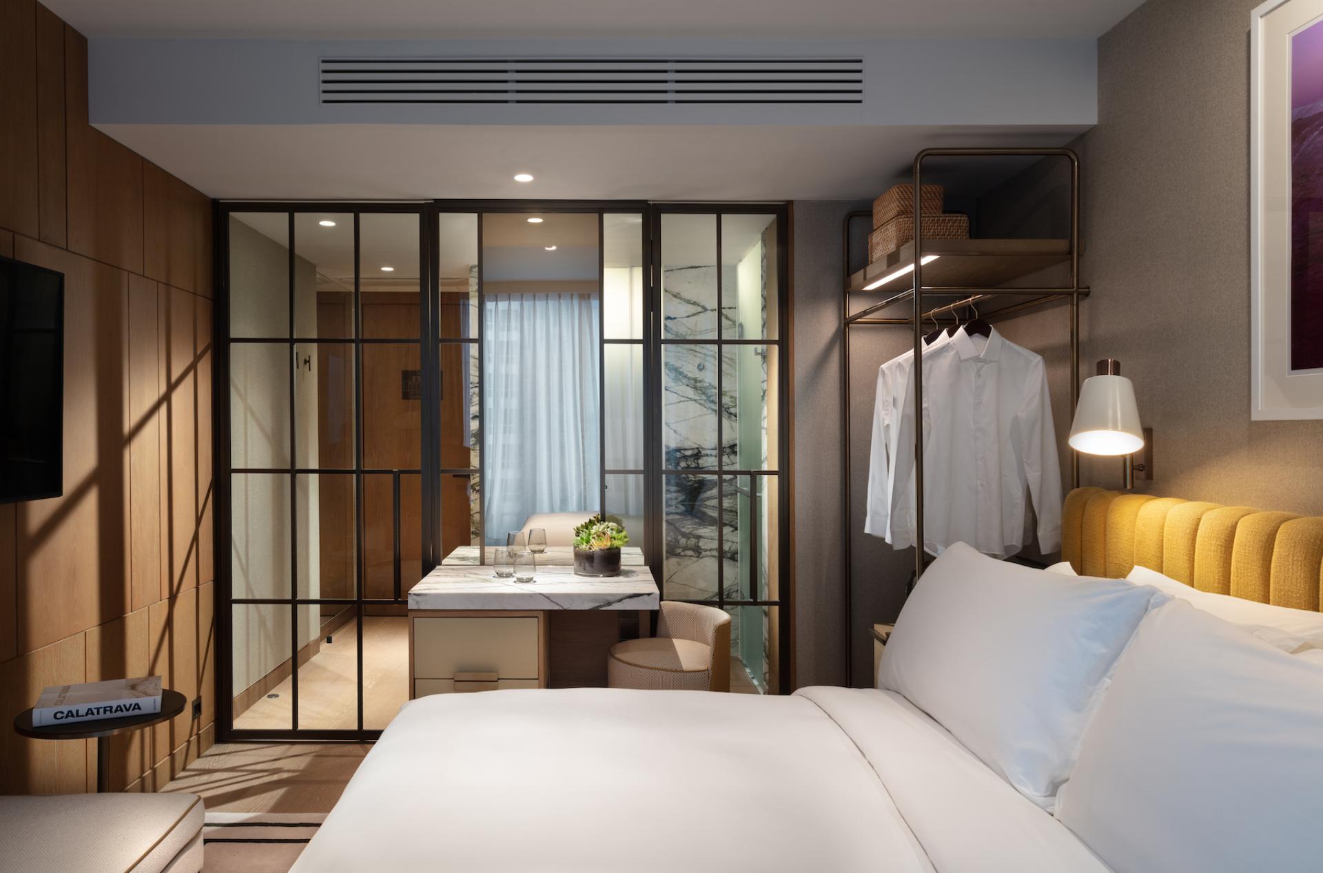 Stylish hotel room at The Hari Hong Kong featuring modern decor, a comfortable bed, and a cozy seating area.