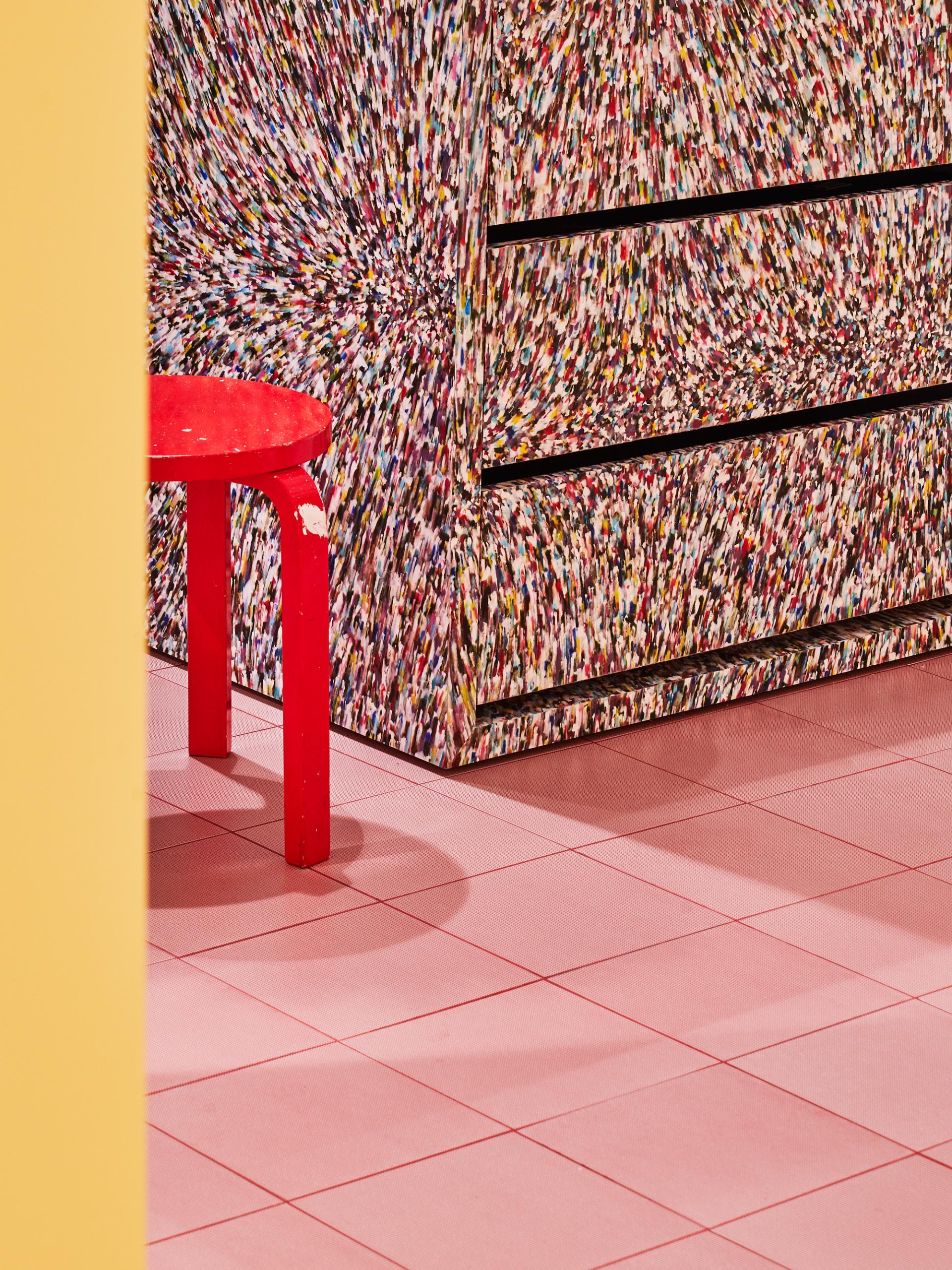 Vibrant red stool beside a colorful patterned dresser, showcasing modern sustainable furniture design at Material Source Studio.