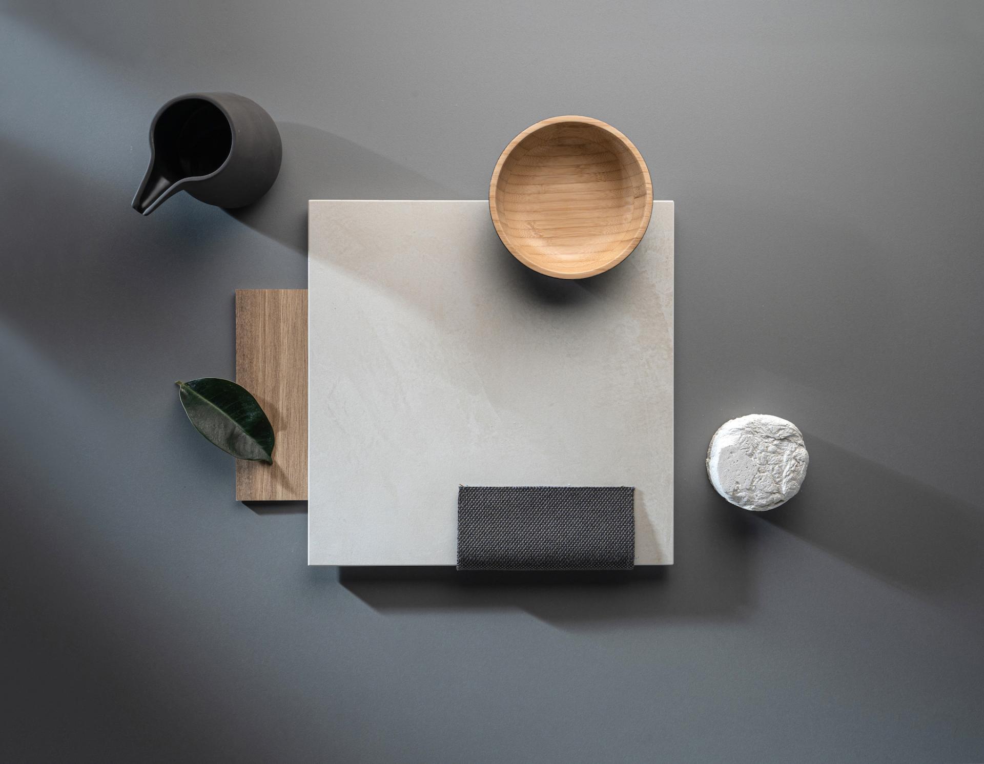 Dekton® Onirika surfaces showcased with natural materials, including a wooden bowl, leafy accents, and textured textiles.