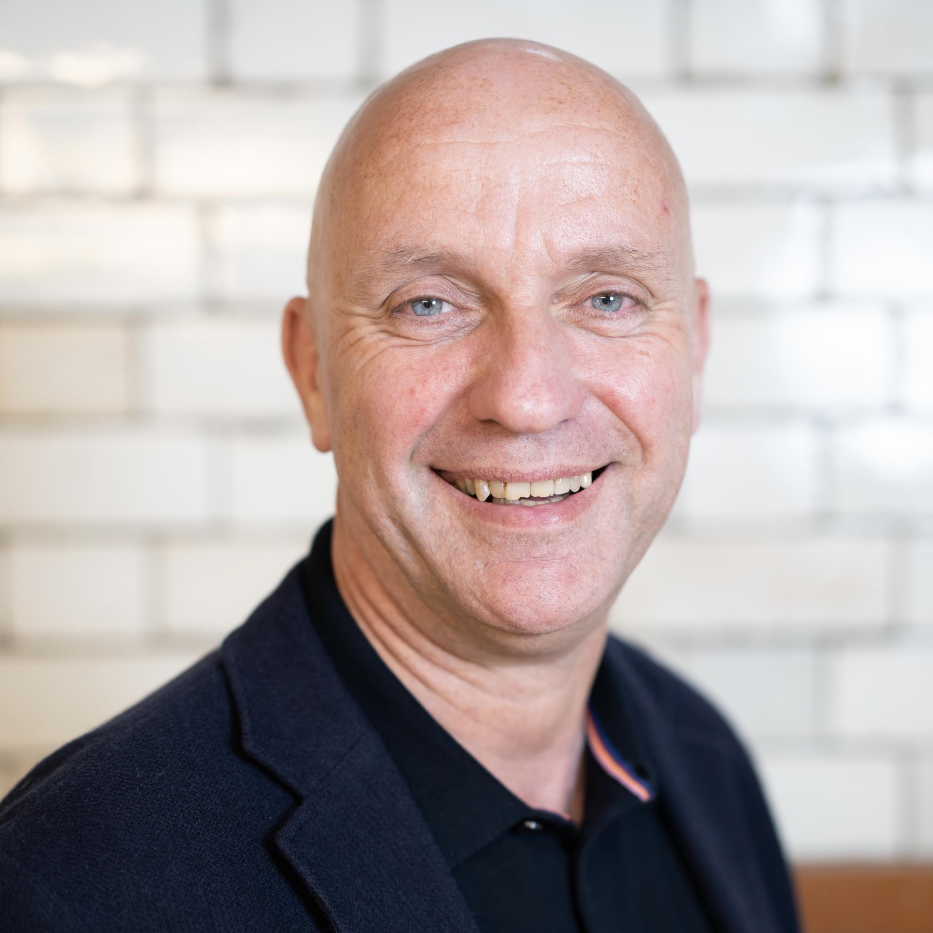 Smiling professional man in a modern workspace, illustrating the positive effects of technology in the workplace.