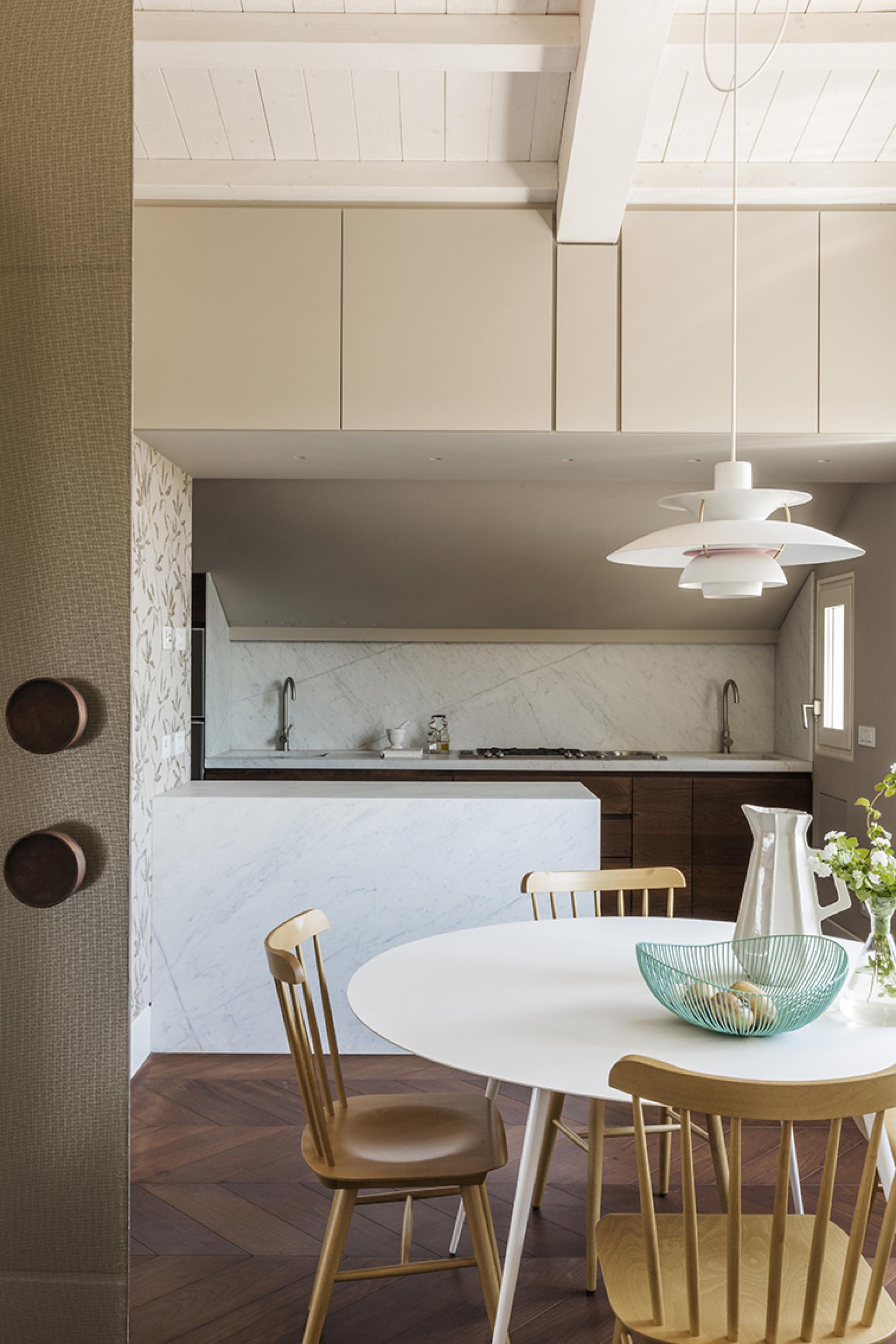 Stylish artist's loft kitchen featuring modern design elements, marble countertops, and a round dining table in Rome.