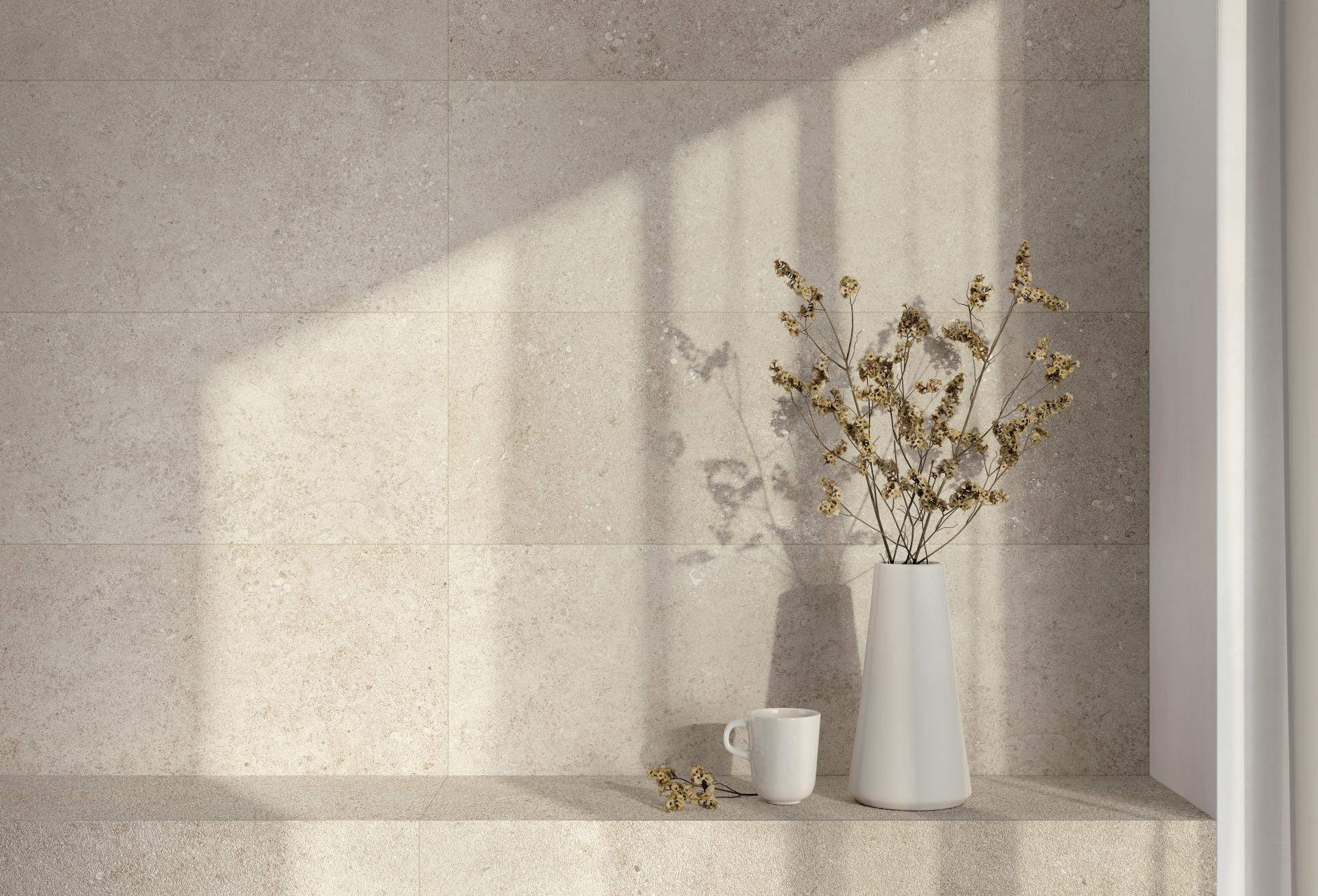 Elegant ceramic tiles serve as a backdrop for a minimalist vase with dried flowers and a coffee cup.