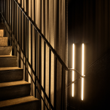 Elegant staircase with warm lighting and textured curtains, highlighting the interior design of the Peoplegrapher Dusseldorf studio.