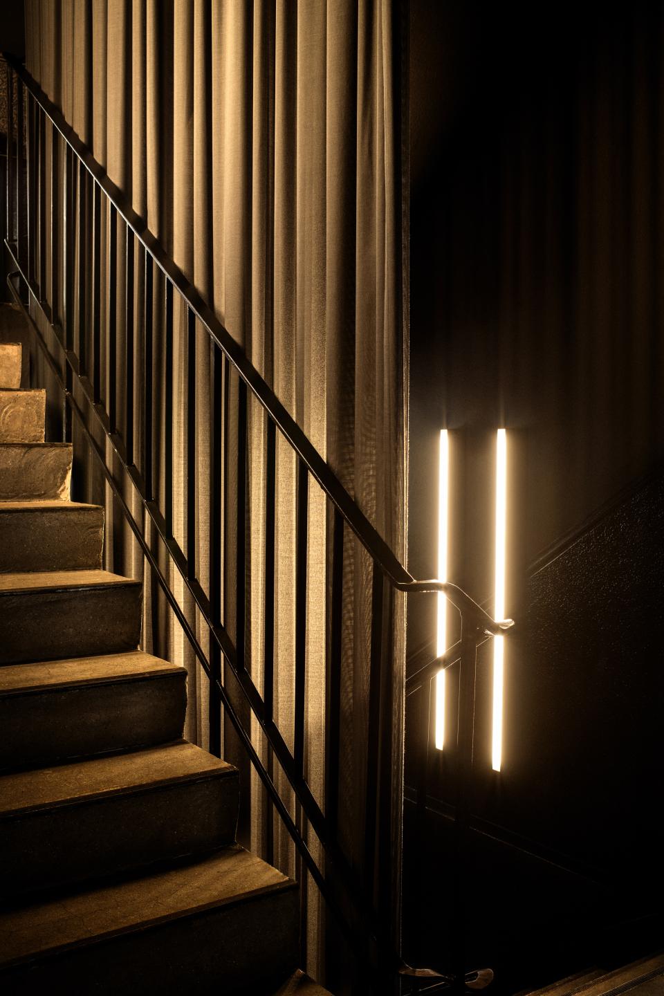 Elegant staircase with warm lighting and textured curtains, highlighting the interior design of the Peoplegrapher Dusseldorf studio.