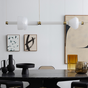 Modern dining setting featuring Gabriel Scott's Luna Kaleido lighting, elegant vases, and abstract wall art, showcasing luxury design.