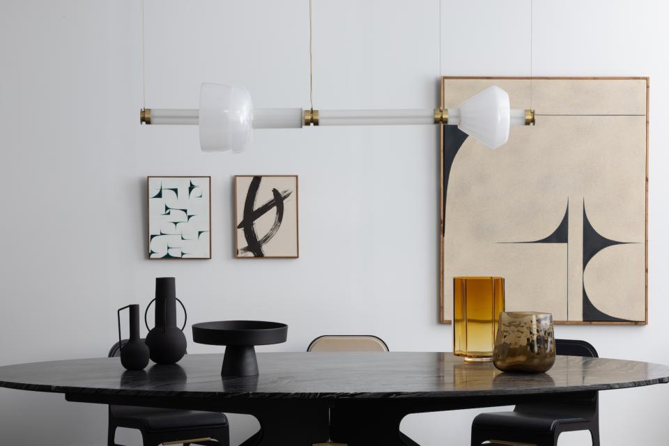 Modern dining setting featuring Gabriel Scott's Luna Kaleido lighting, elegant vases, and abstract wall art, showcasing luxury design.