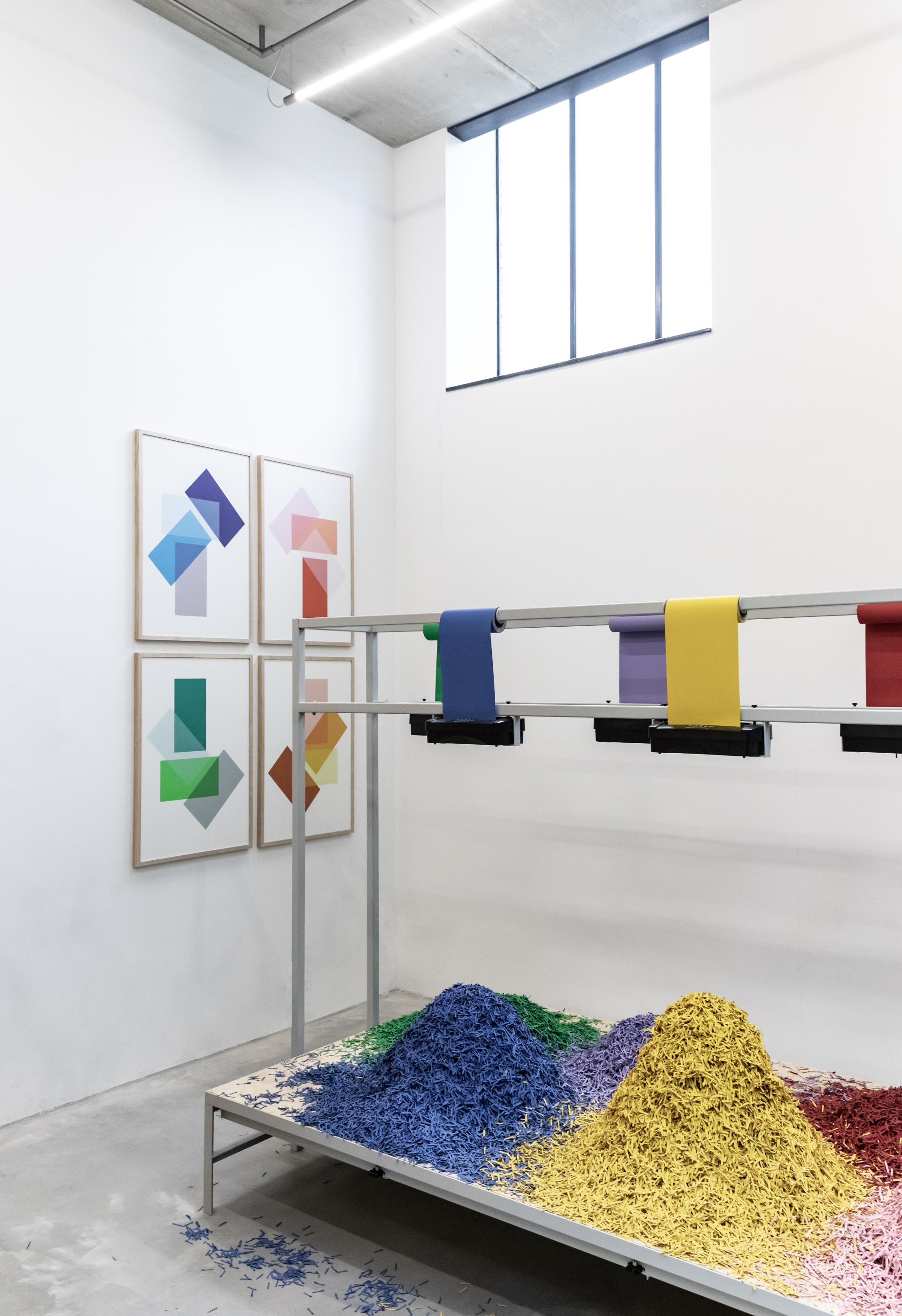 Display of vibrant bio-based color palettes alongside abstract geometric artwork in a modern artistic space.