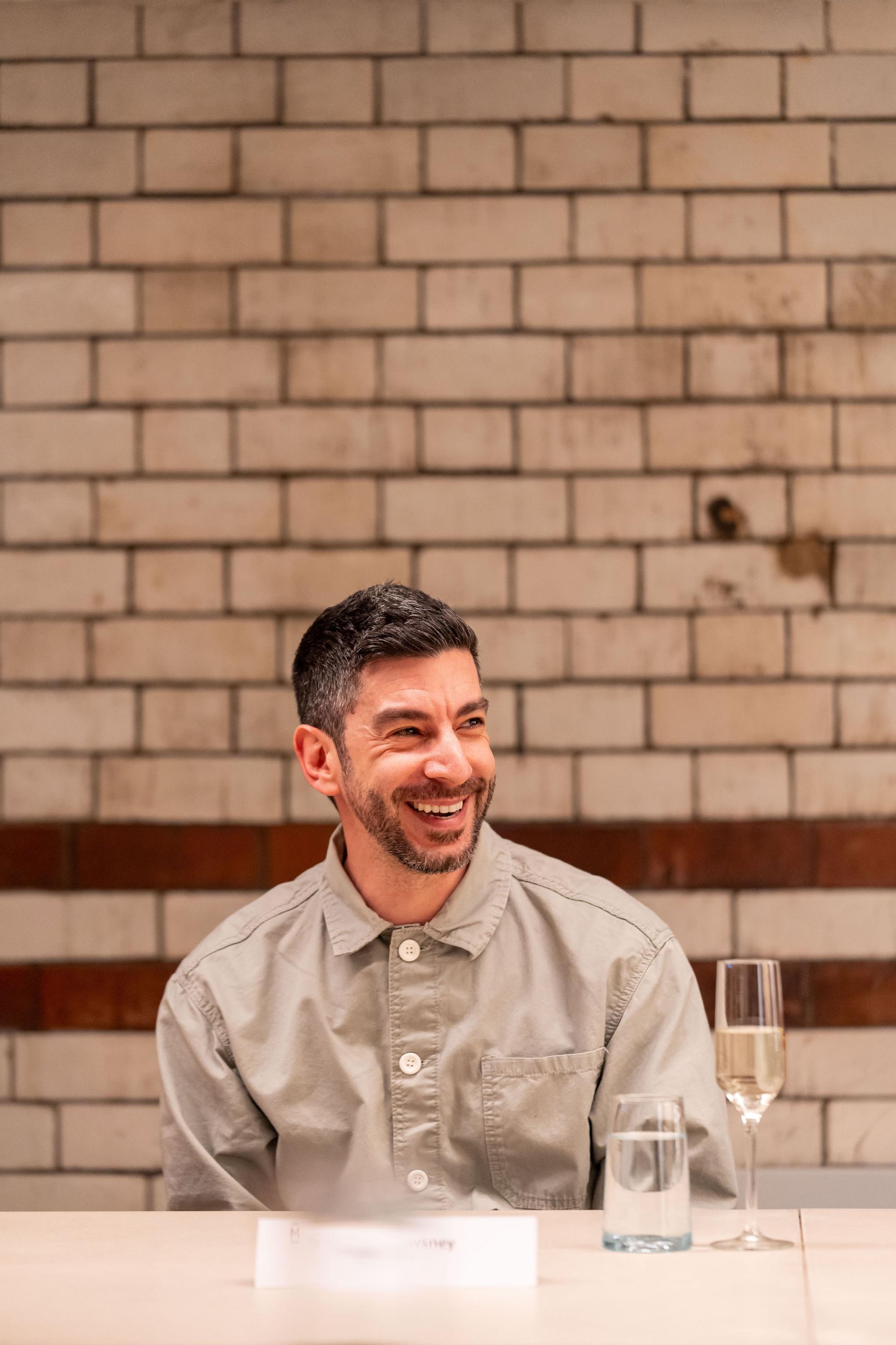 Participant engaged in discussion about sustainability and value engineering at a roundtable event, smiling with drinks nearby.