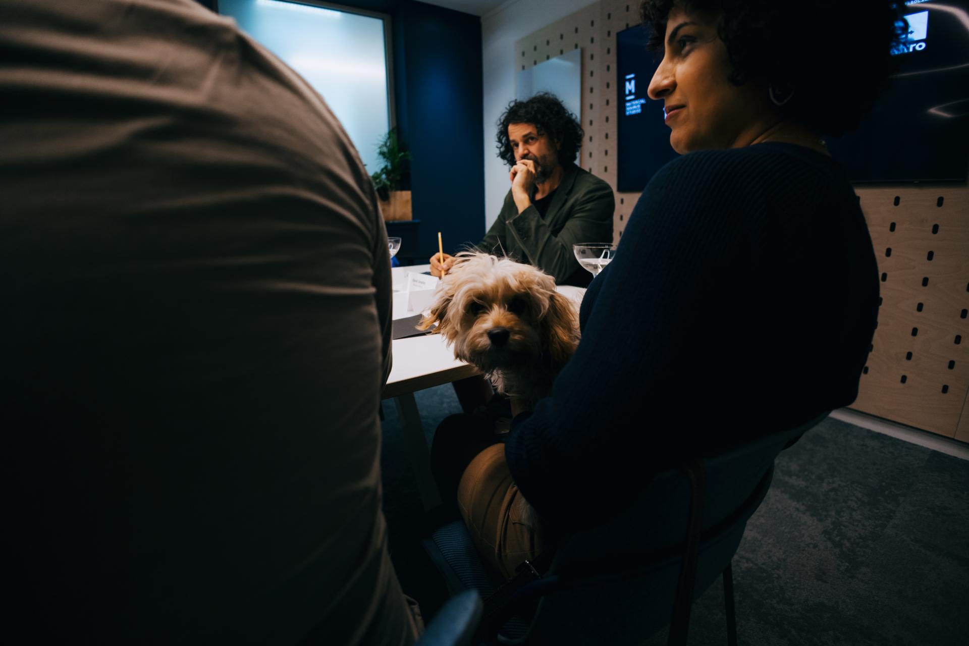 A roundtable discussion on neurodiversity featuring a dog, with participants engaged in conversation at Material Source Studio.