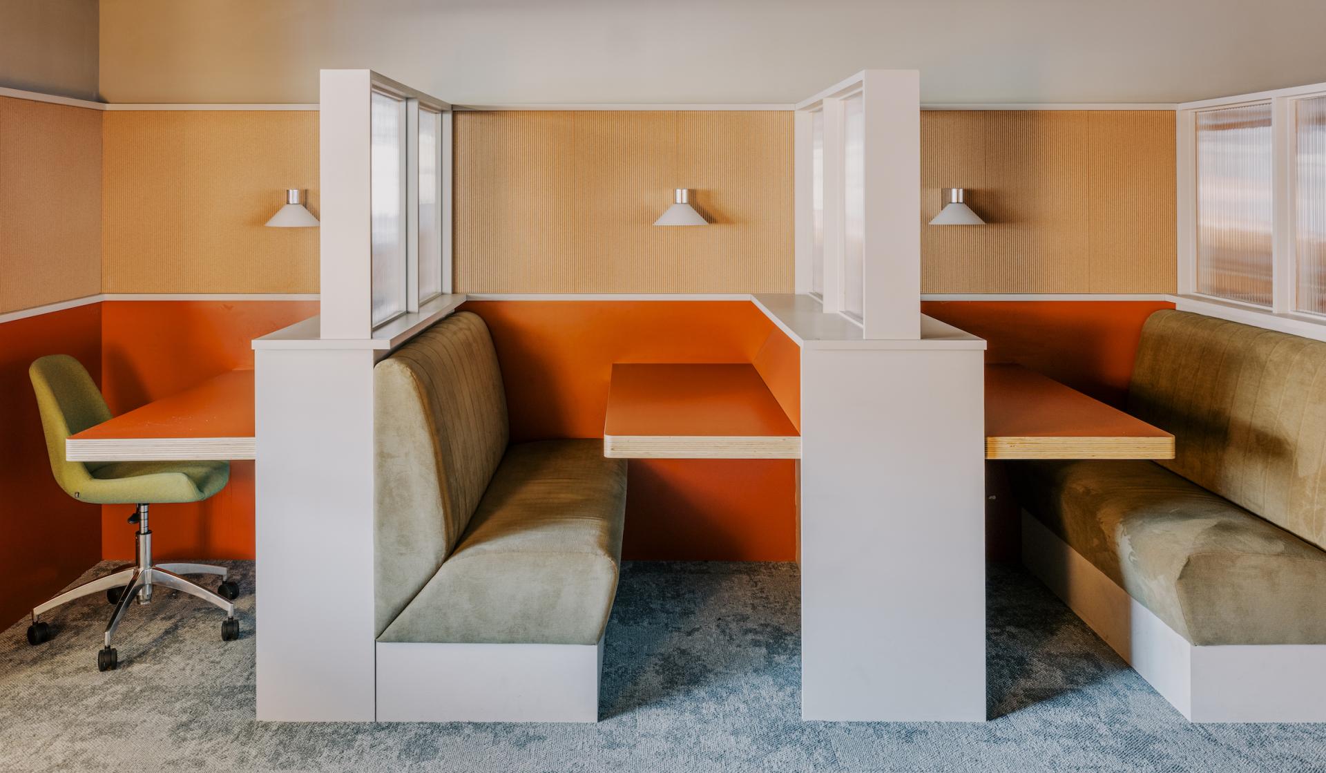Modern study booths with green seating and orange accents, designed for iQ East Court, reflecting Mile End's historic inspiration.