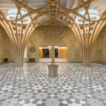 Elegant interior of Cambridge Central Mosque showcasing innovative wooden architecture and intricate patterned flooring.