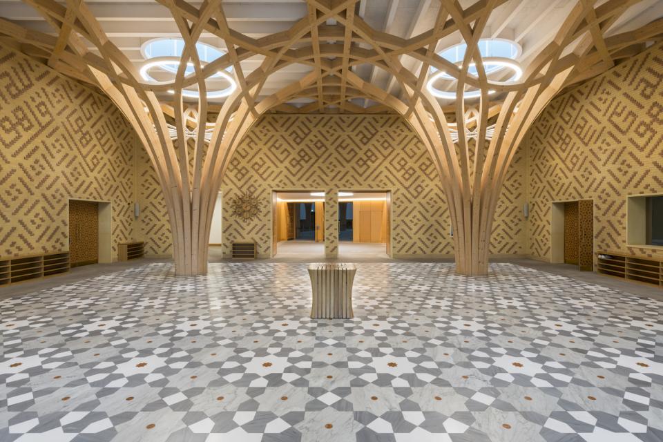 Elegant interior of Cambridge Central Mosque showcasing innovative wooden architecture and intricate patterned flooring.
