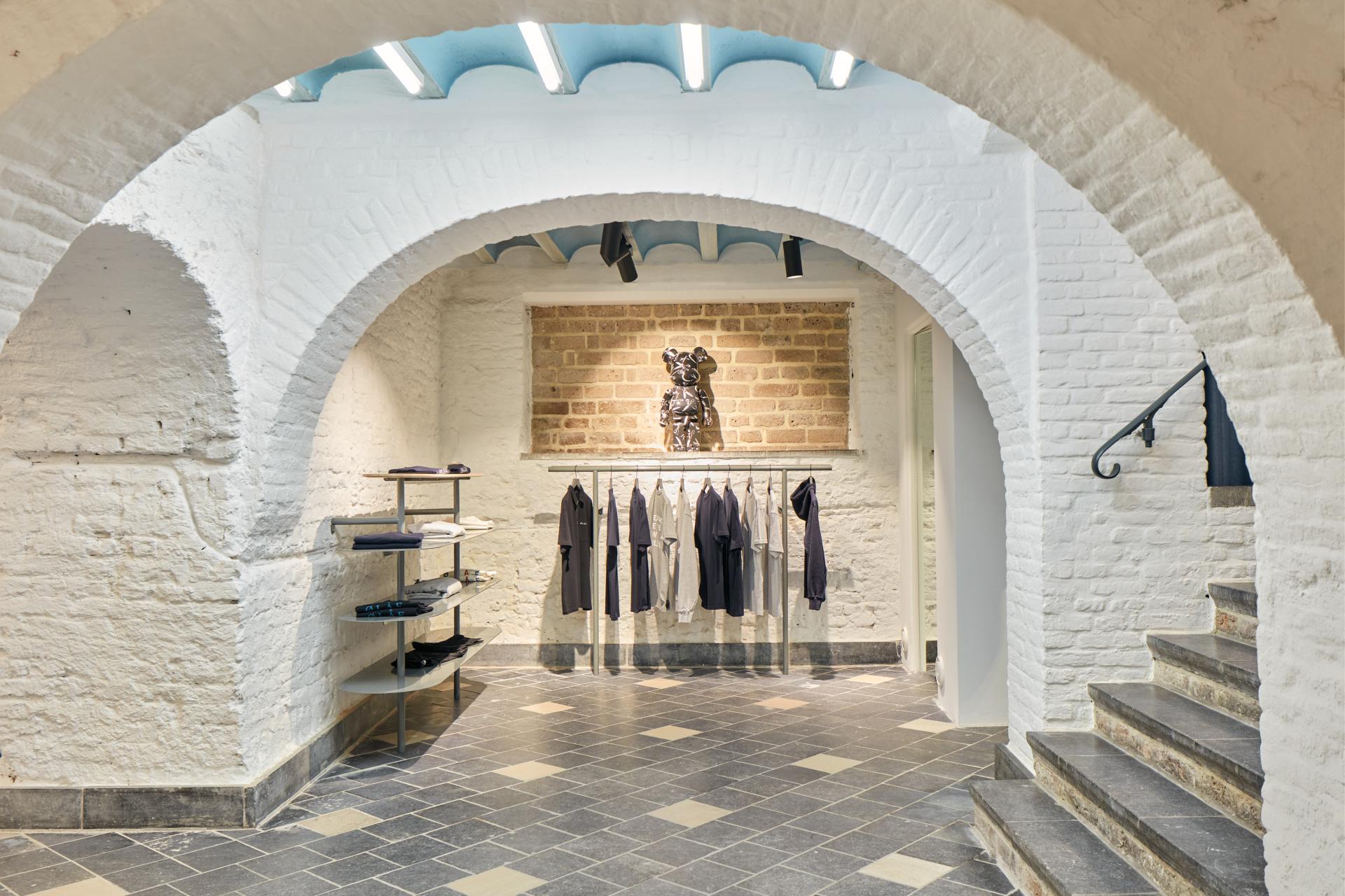 Interior of the COEF shop in Utrecht, featuring clothing displays, unique lighting, and historic brick architecture.