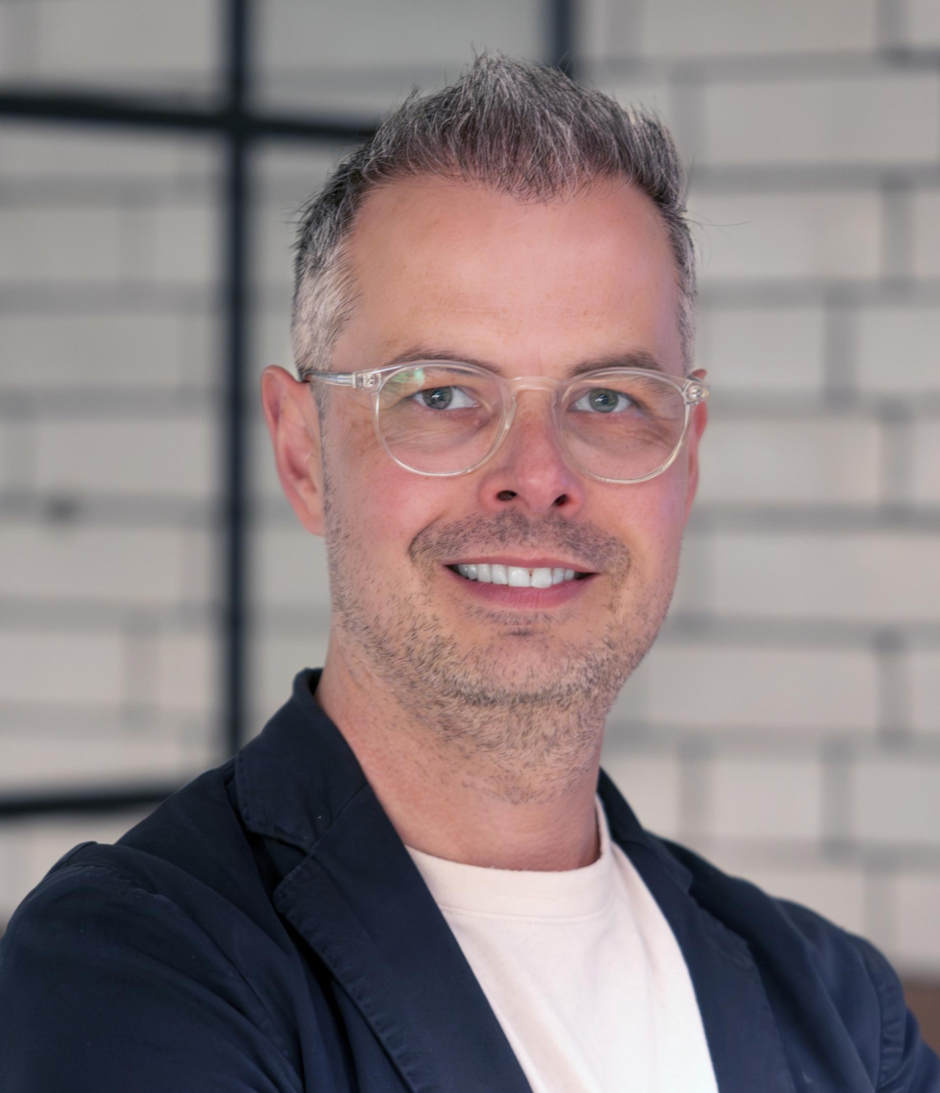Professional smiling man in a modern setting, discussing Manchester's residential property mix during a seminar.
