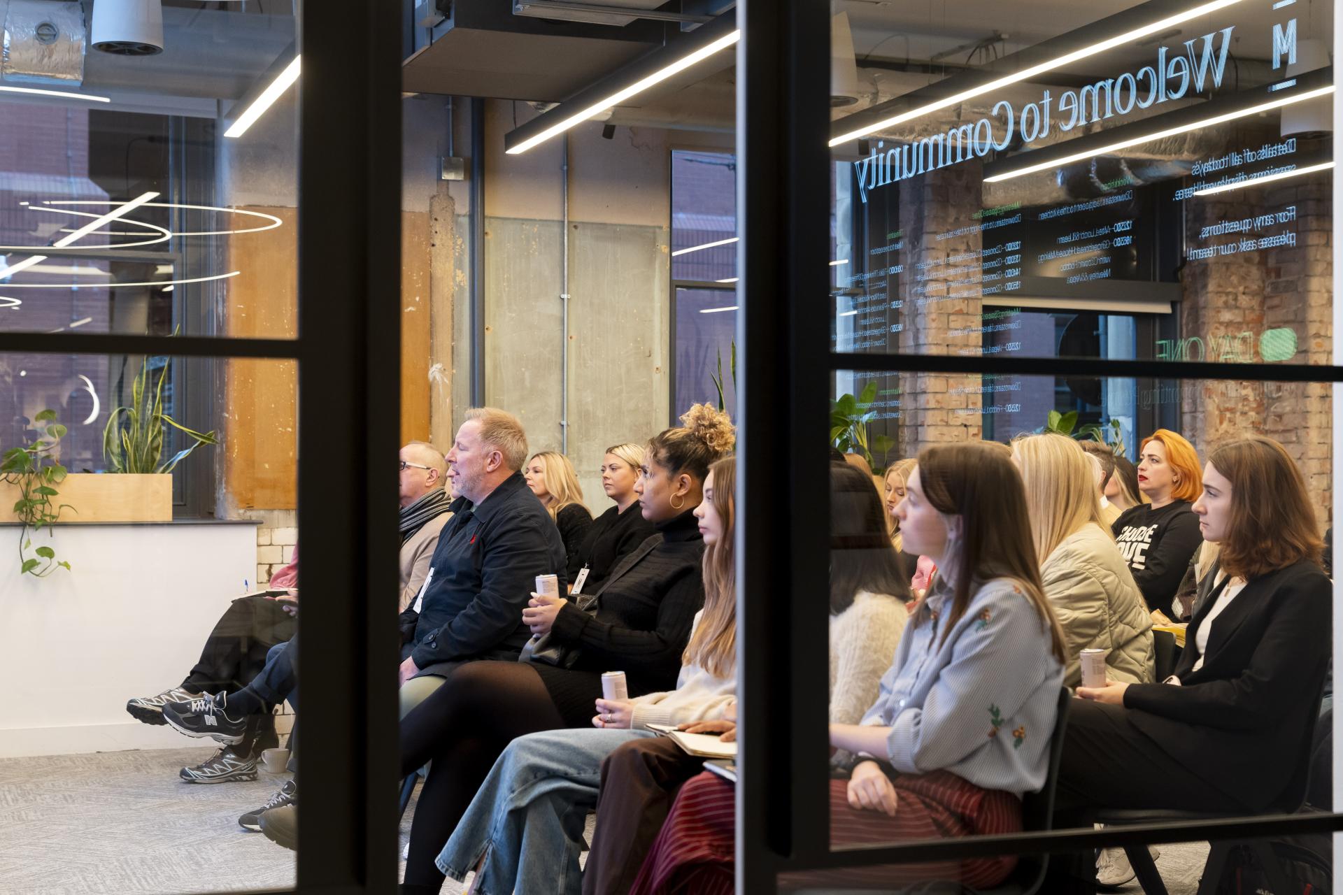 Diverse audience attentively listening during a presentation on inclusive design for neurodiversity and non-visible disabilities.