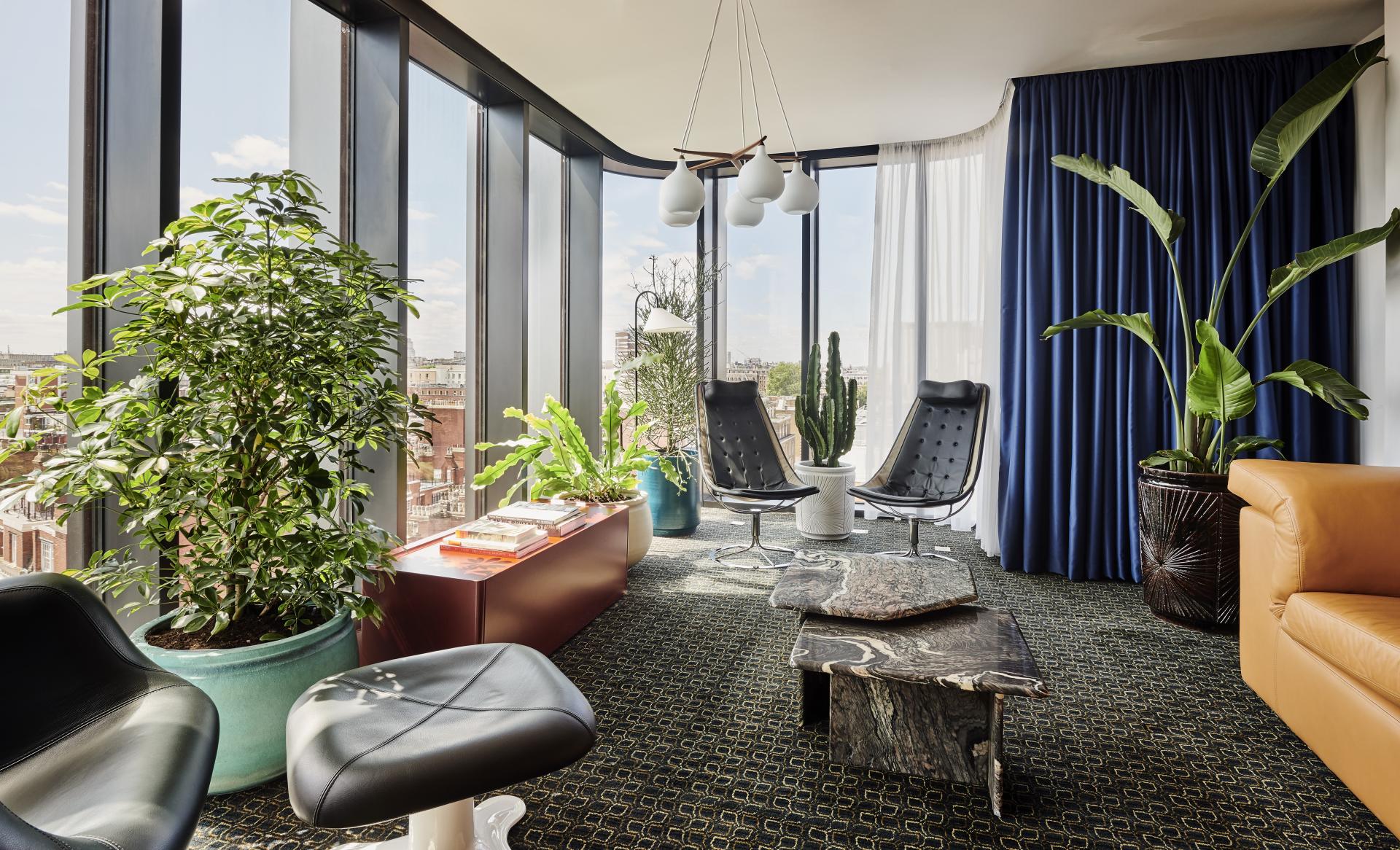 Modern lounge area at The Standard, London, featuring elegant furniture, vibrant plants, and large windows with city views.