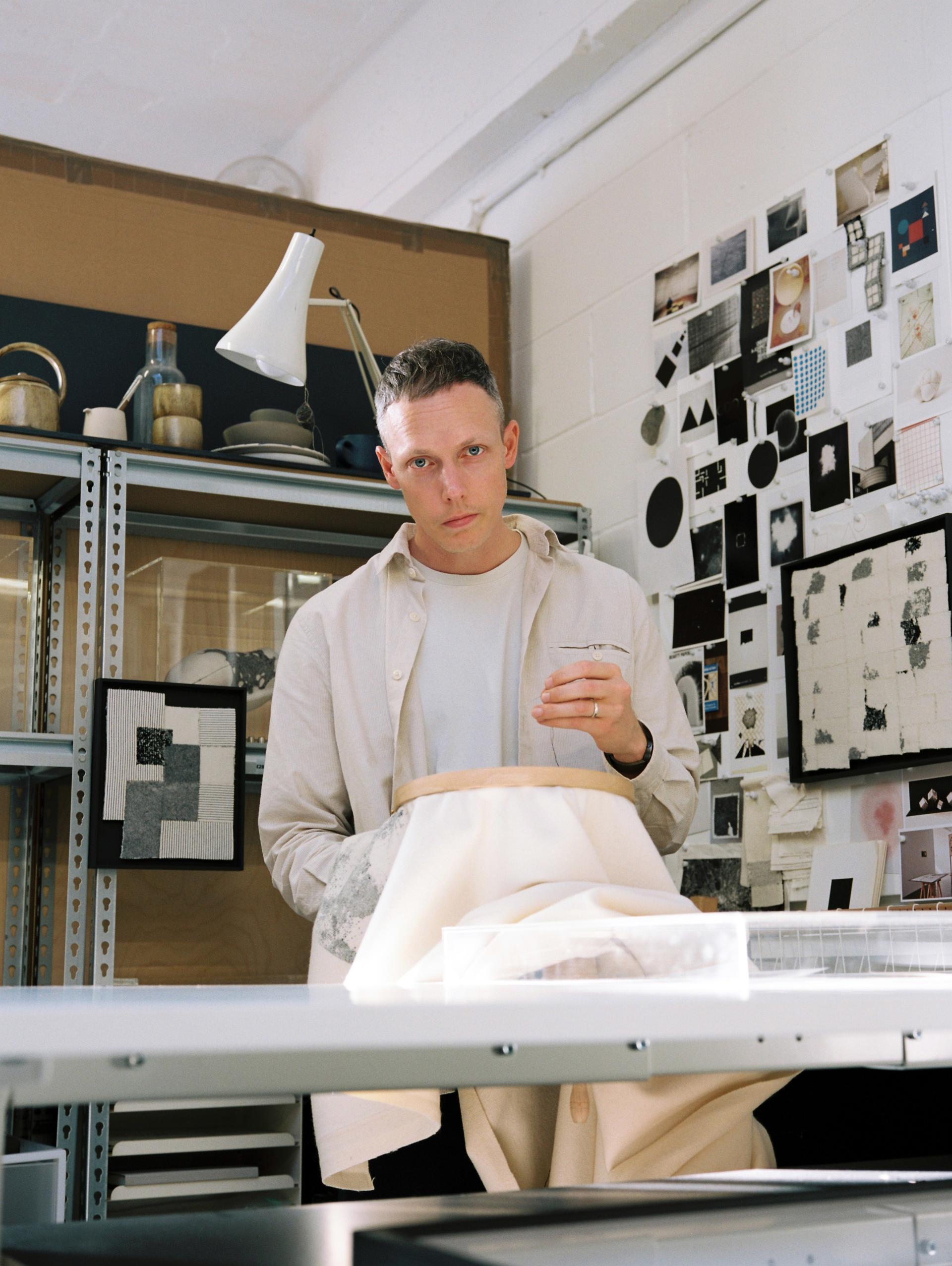 Designer working on fabric in a creative studio, surrounded by art and materials during London Craft Week 2024.