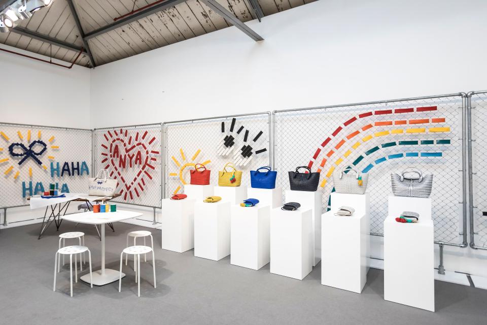 Colorful Anya Hindmarch handbags displayed in an immersive installation featuring playful art elements at London Fashion Week.