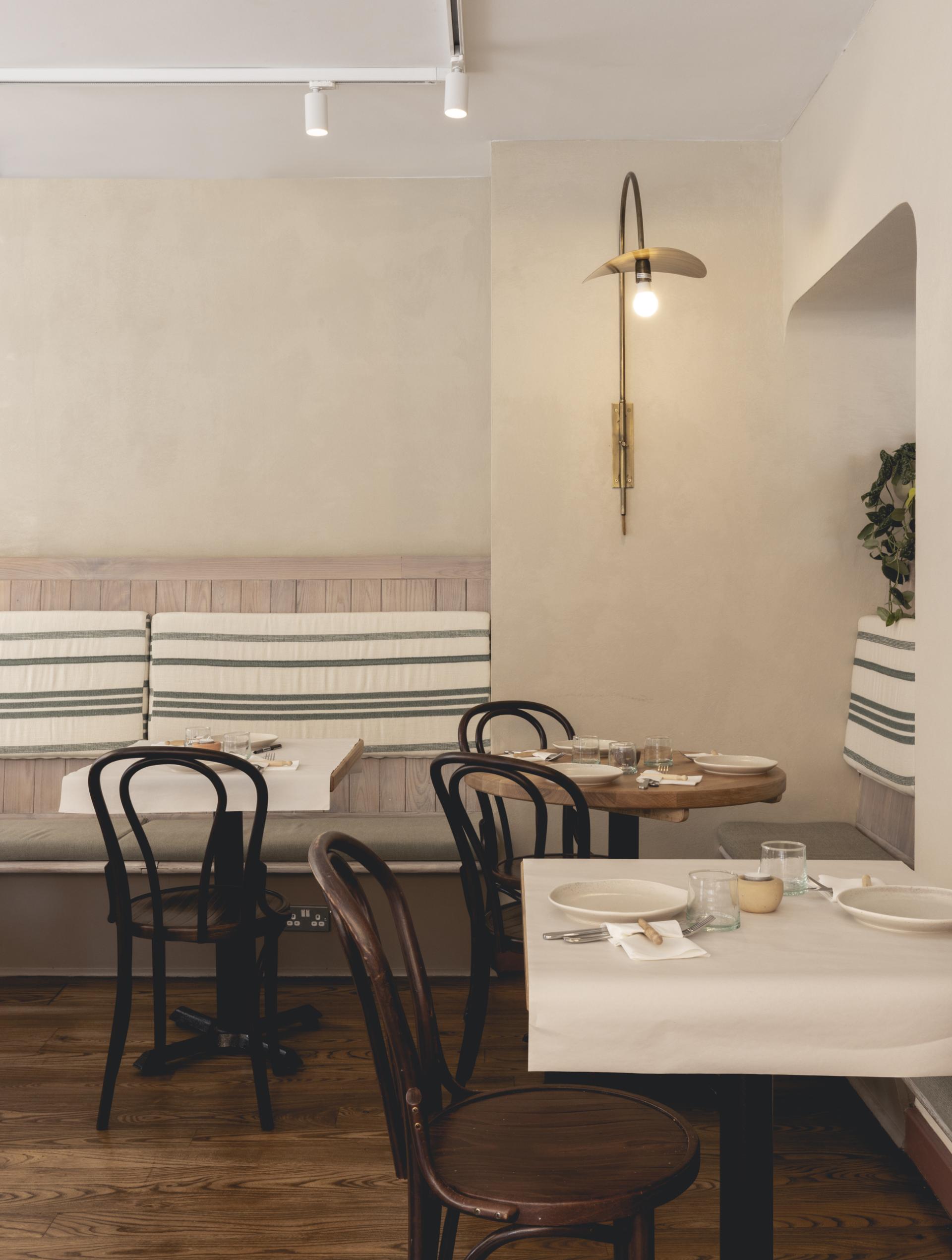 Elegant interior of Honey & Co Bloomsbury, featuring wooden tables, vintage chairs, and warm lighting.