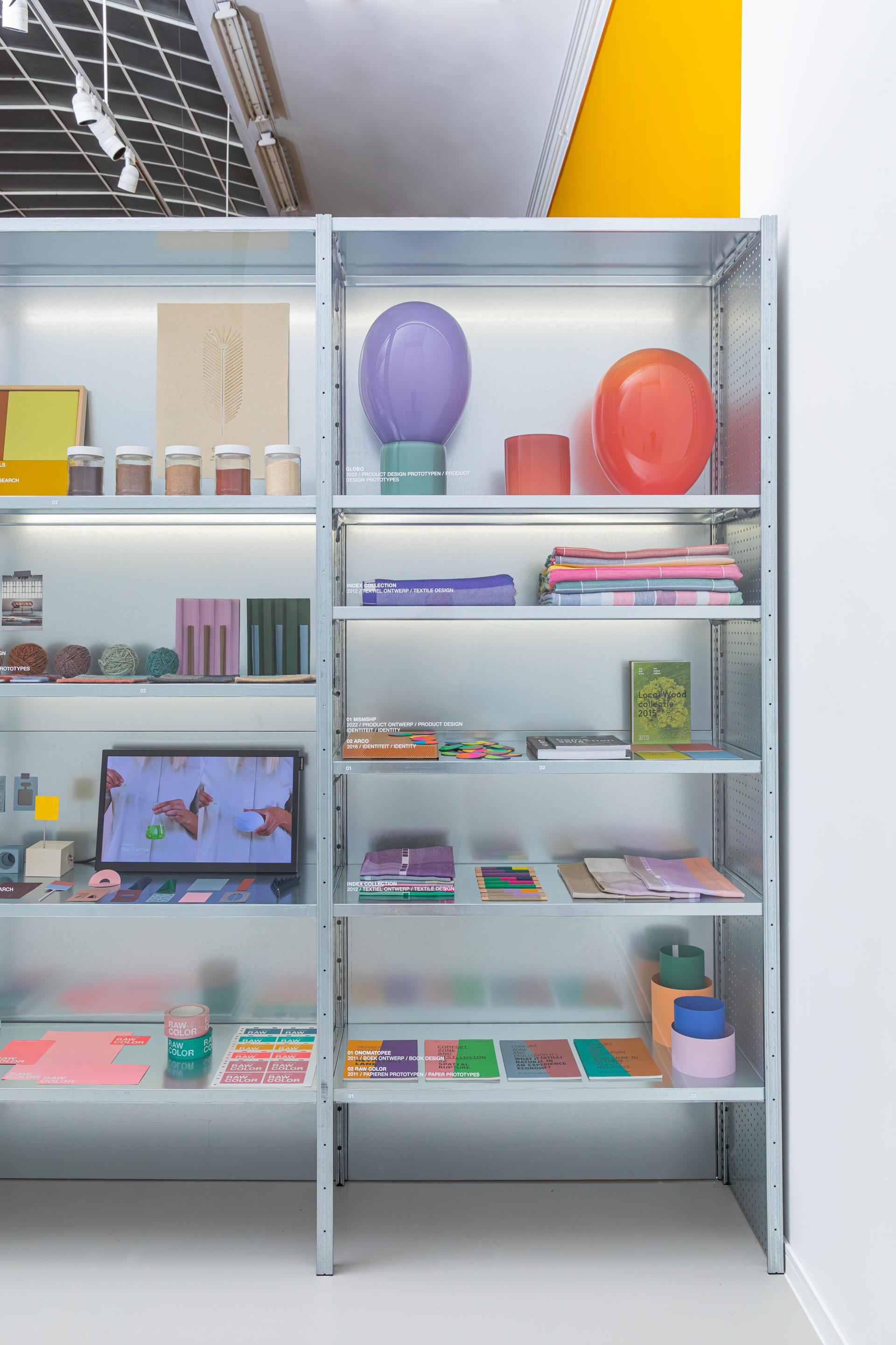 Shelves displaying bio-based color palettes, design materials, and digital presentations showcasing Raw Color's innovative approach.