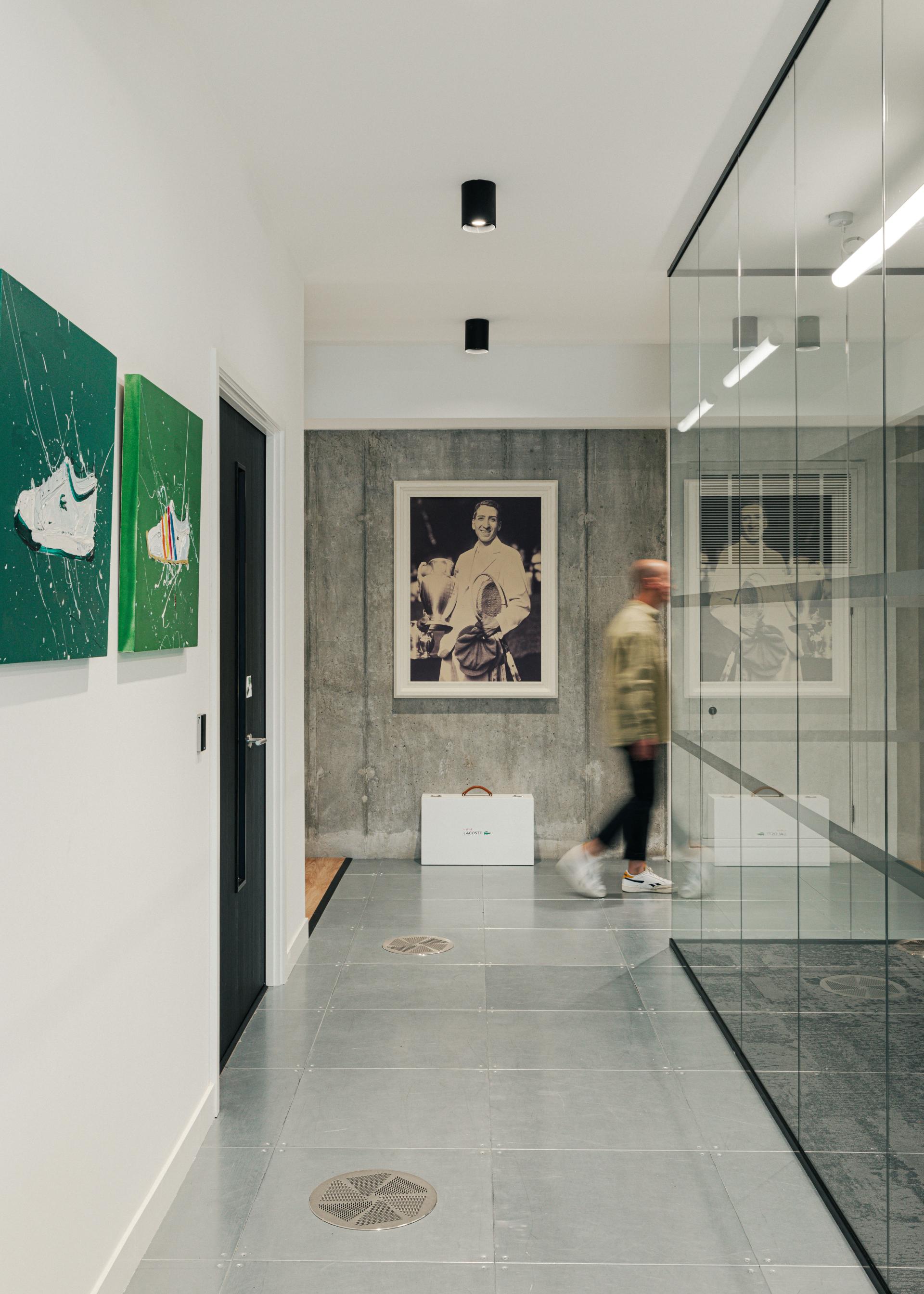 Modern hallway showcasing Lacoste shoe artwork and a concrete wall, embodying a stylish New York warehouse aesthetic.