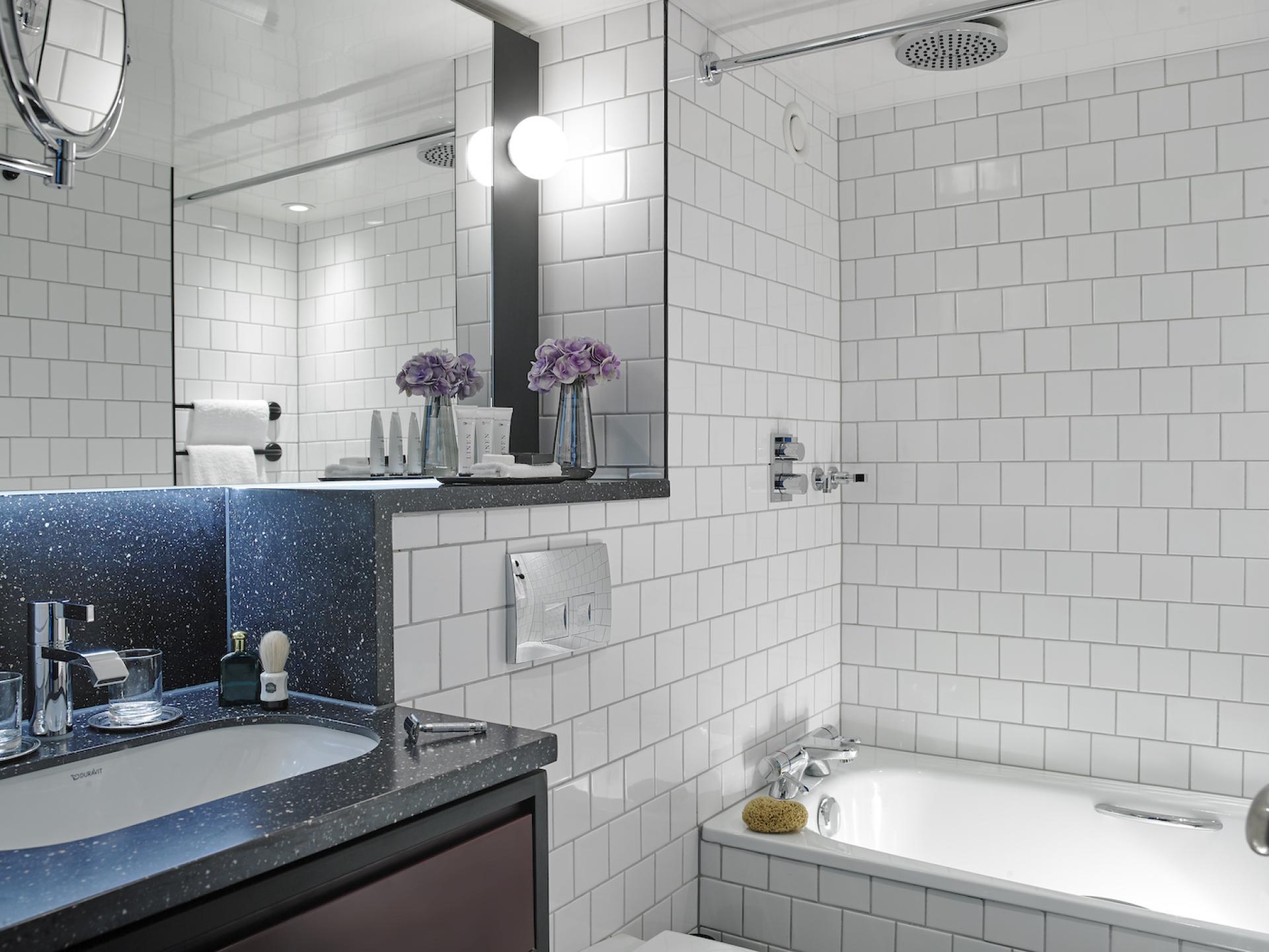 Modern hotel bathroom featuring sleek design, clean white tiles, contemporary fixtures, and floral accents for a chic atmosphere.