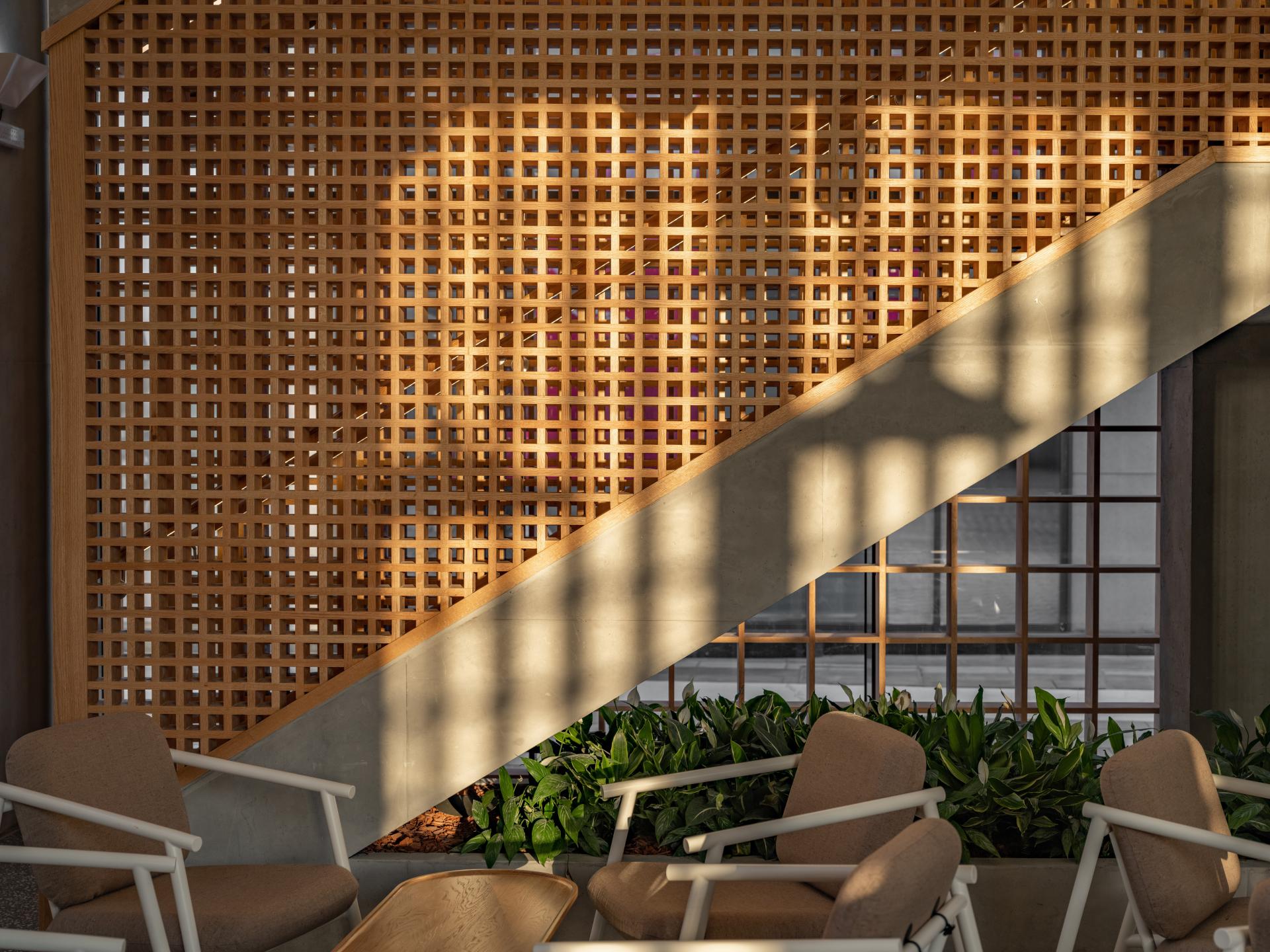 A modern coffee shop interior featuring a wooden lattice design and soft seating, exemplifying a Japandi aesthetic.