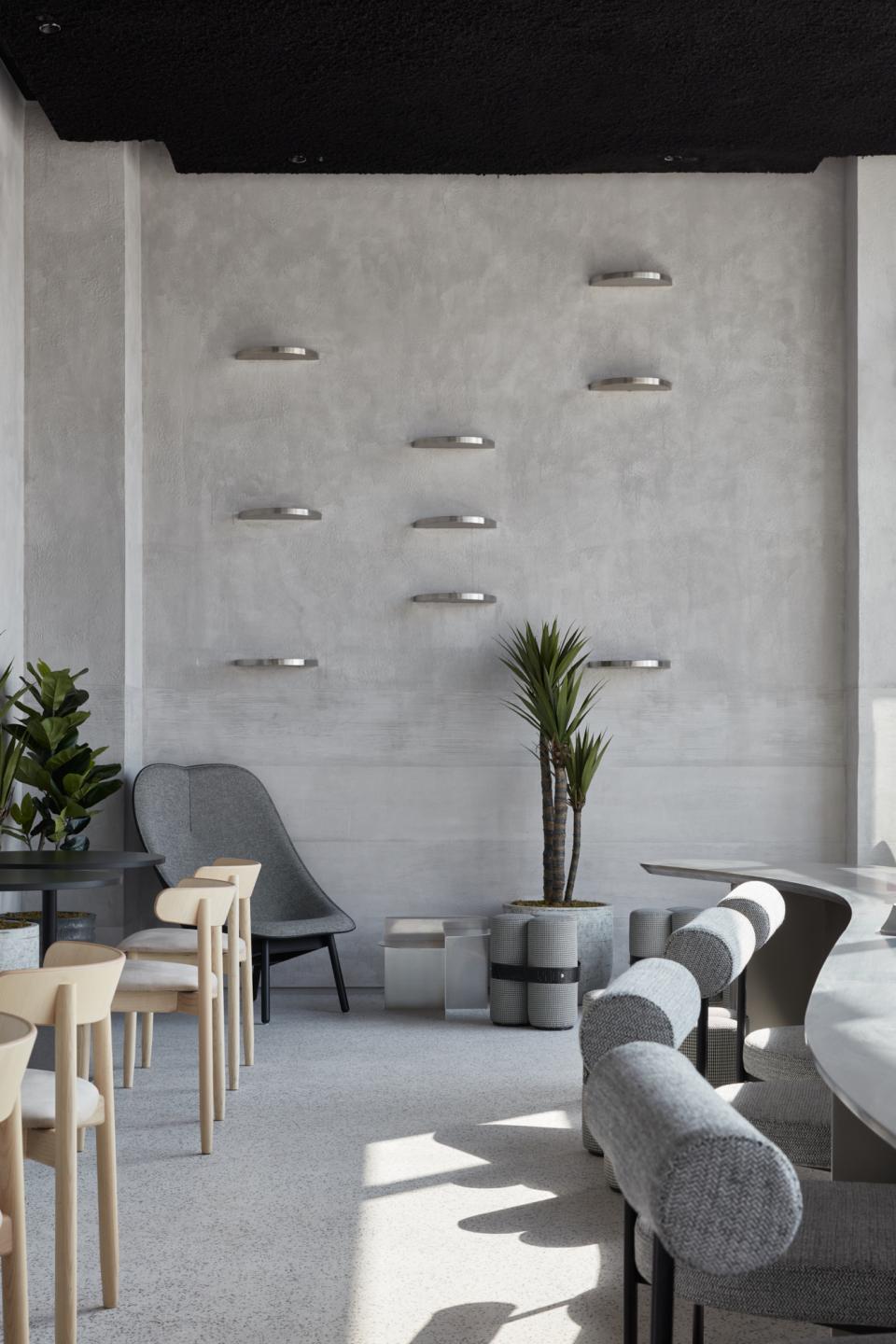 Stylish minimalist interior of Drop Coffee in Abu Dhabi, featuring textured walls, modern furniture, and potted plants.