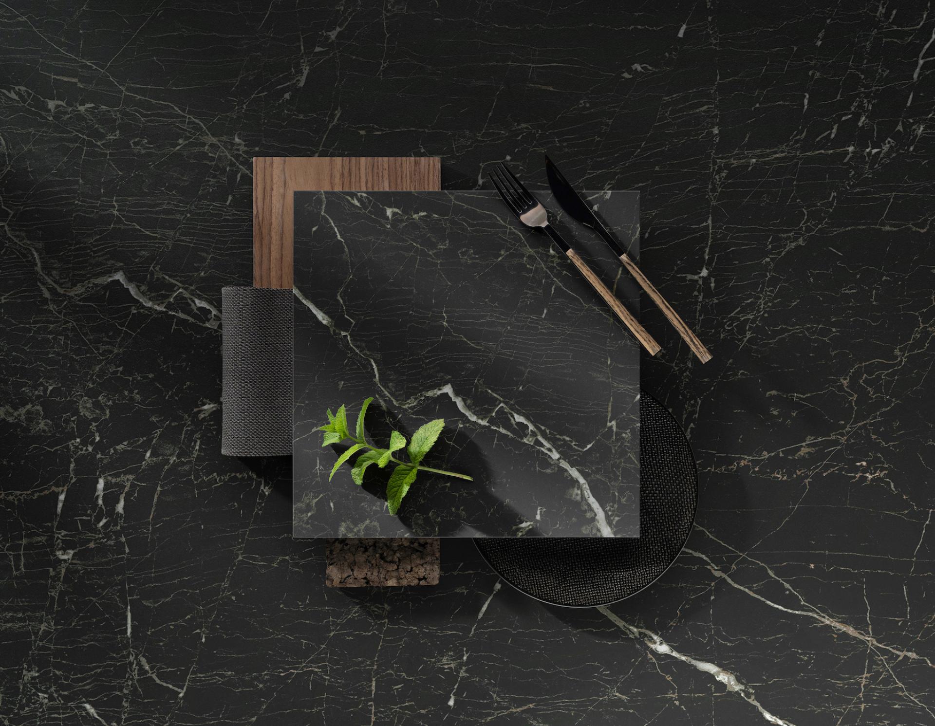Dekton® Onirika collection displayed with elegant black stone surfaces, accompanied by natural elements like herbs and stylish utensils.