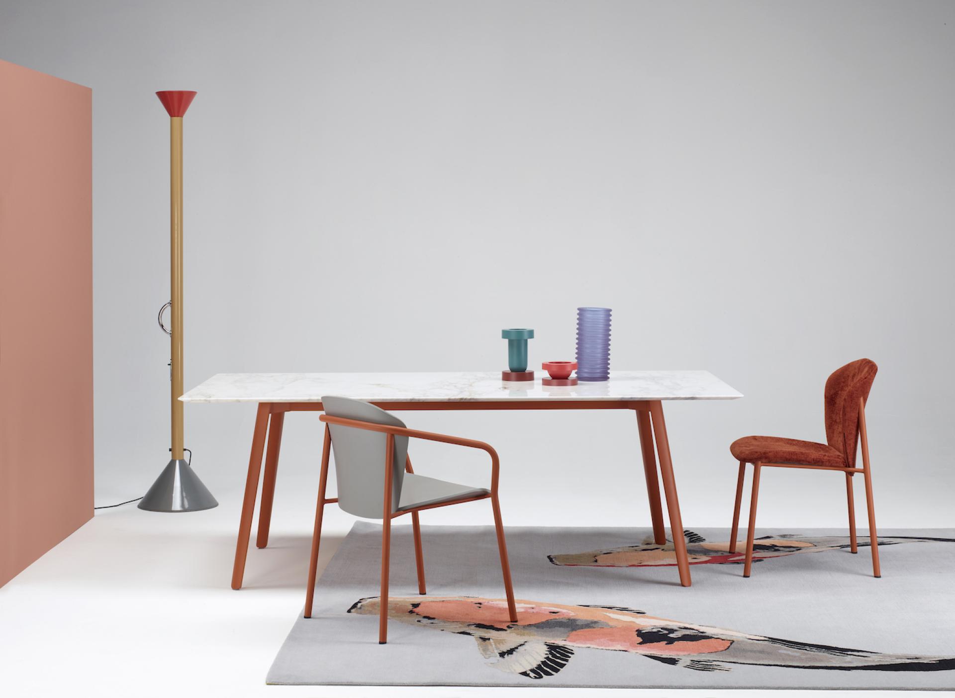 Stylish dining area featuring a cuttlefish-inspired table, colorful tableware, and contemporary chairs on a decorative rug.
